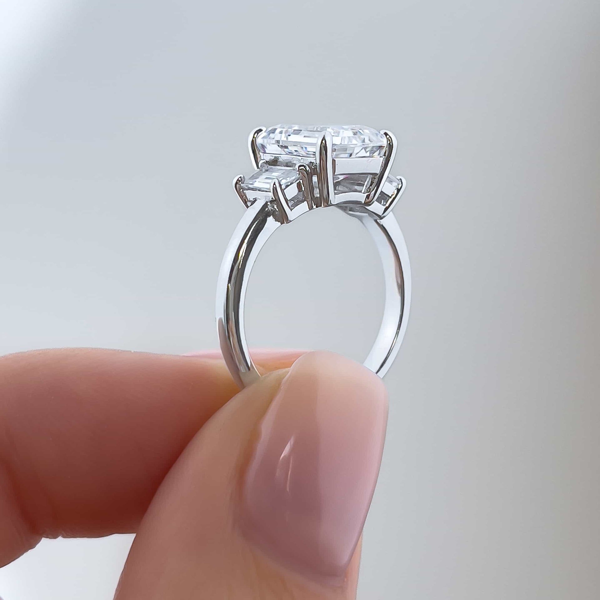 setting shot of a stunning silver emerald cut trio engagement ring