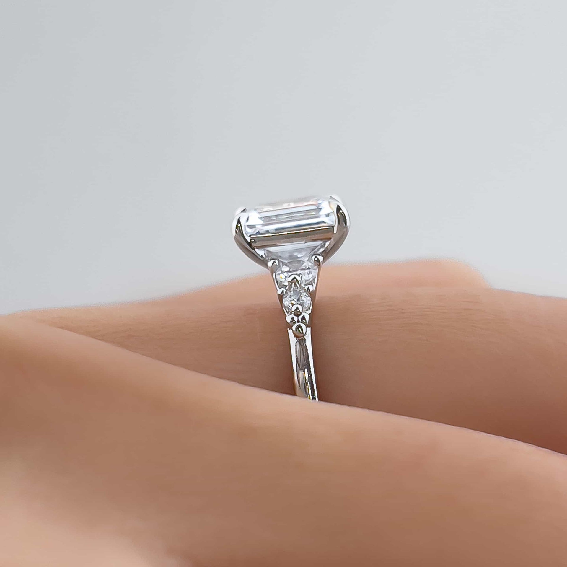 side shot of silver 1.5 carat emerald cut engagement ring