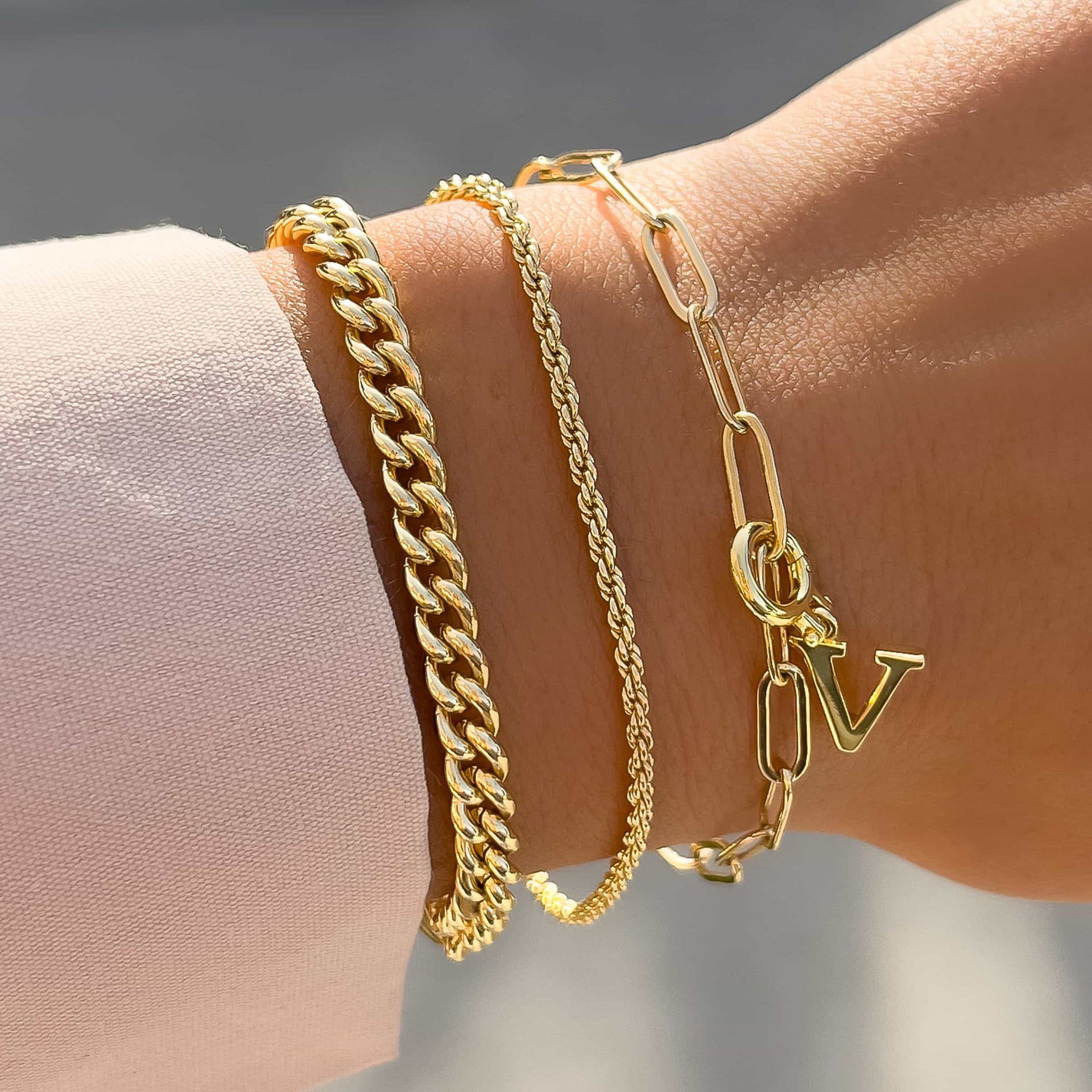 minimalist gold bracelet stack featuring the gold letter charm in "V" on model with neutral top