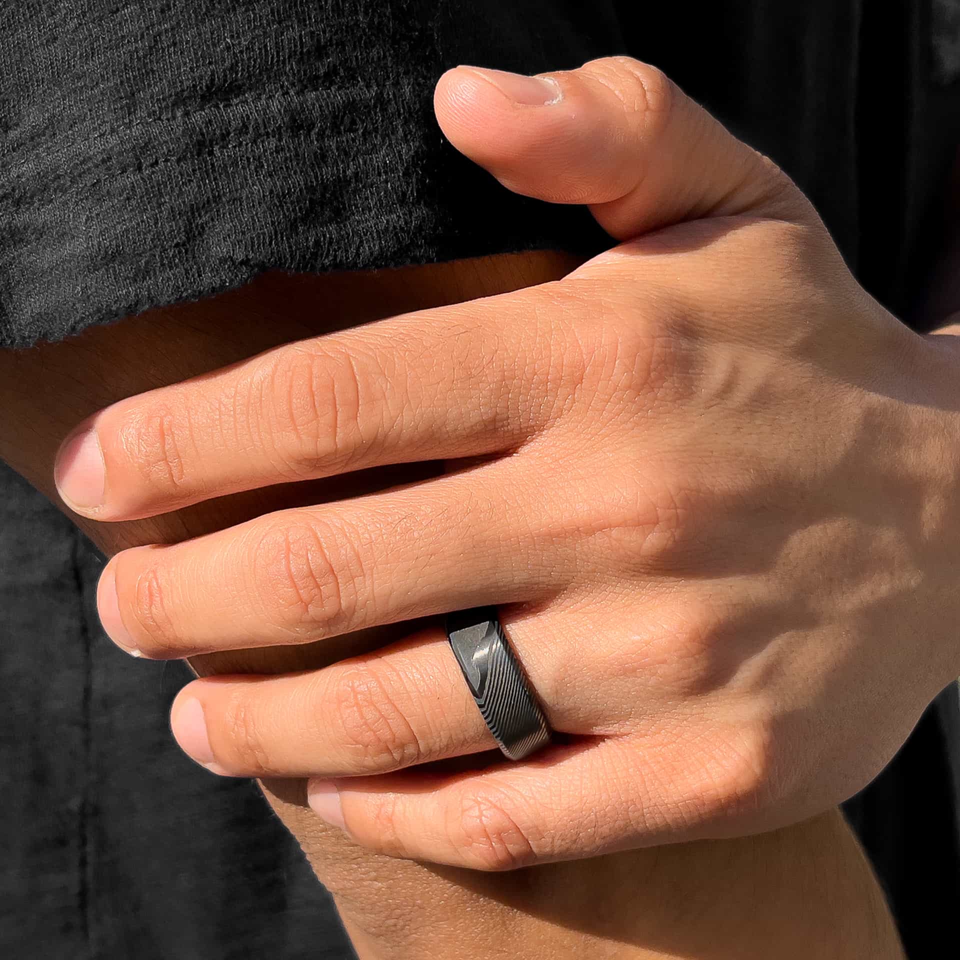 stunning slate colored mens wedding ring on man's hand with black shirt