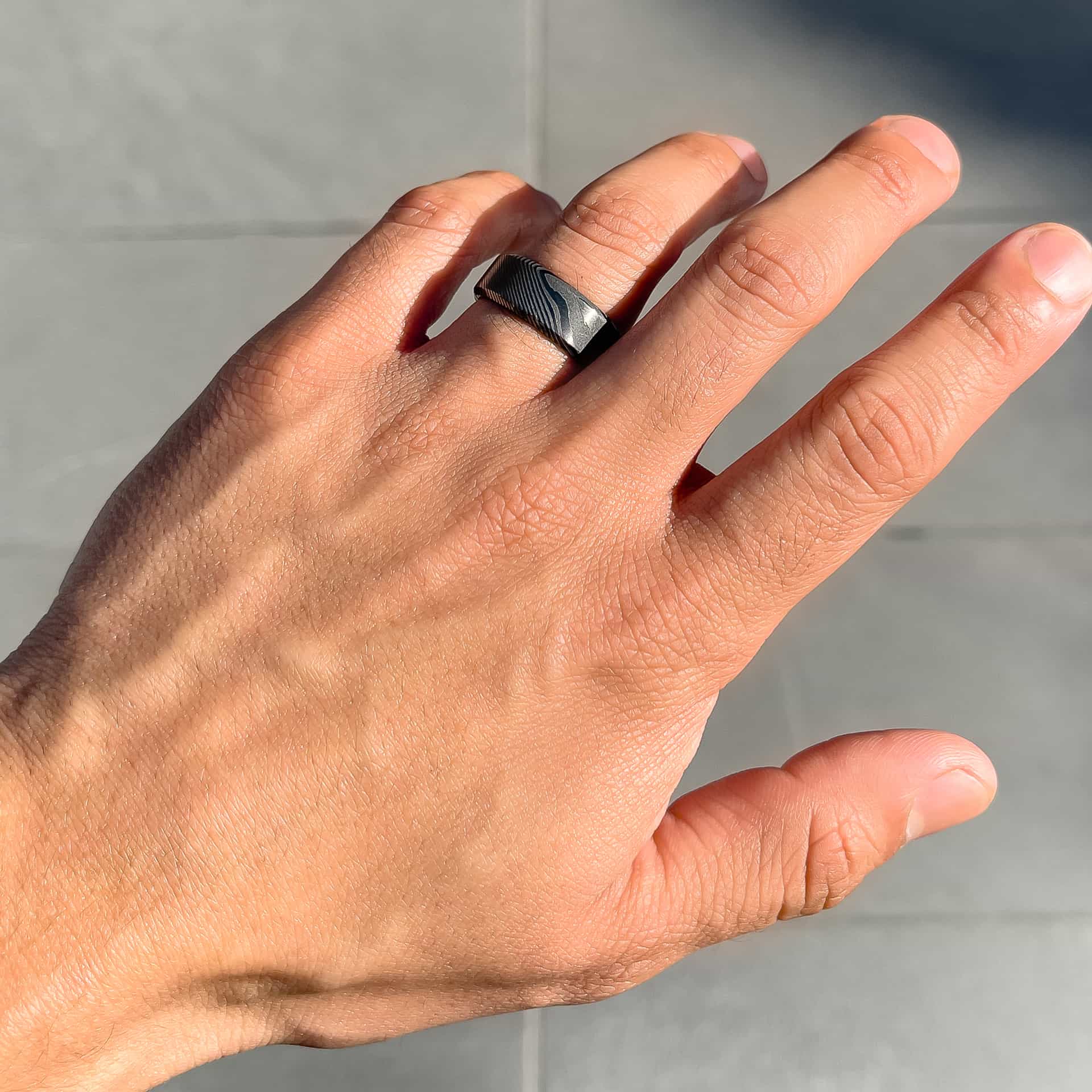 stunning slate colored mens wedding ring shown on man's hand 