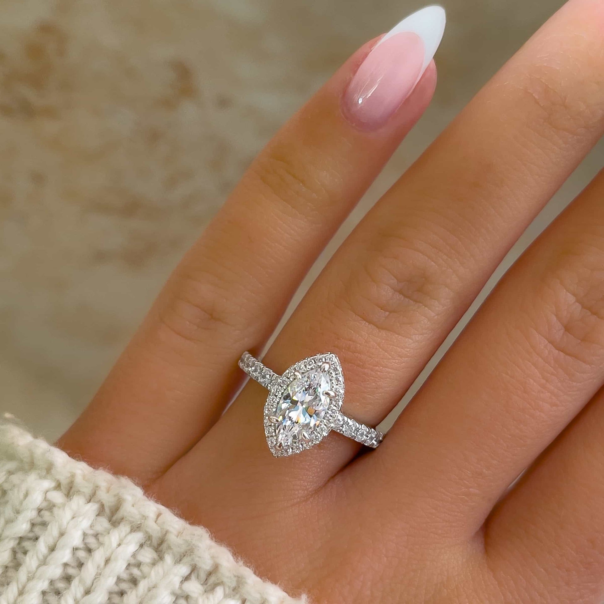 1 carat marquise cut engagement ring with halo and half eternity band detail on model with French tip nails