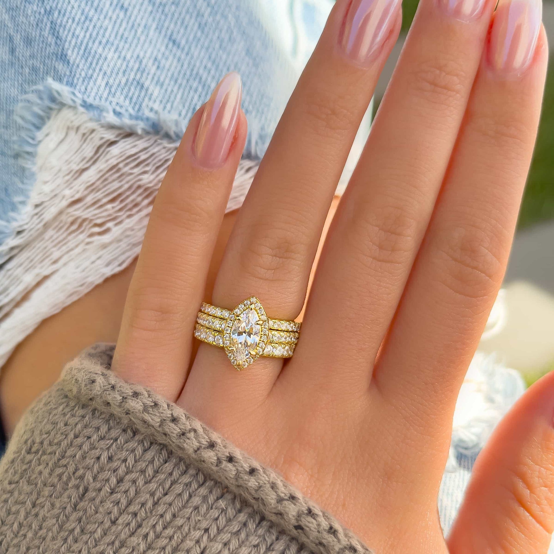 stunning 2 carat marquise cut gold triple wedding ring stack on model with ripped jeans and tan sweater