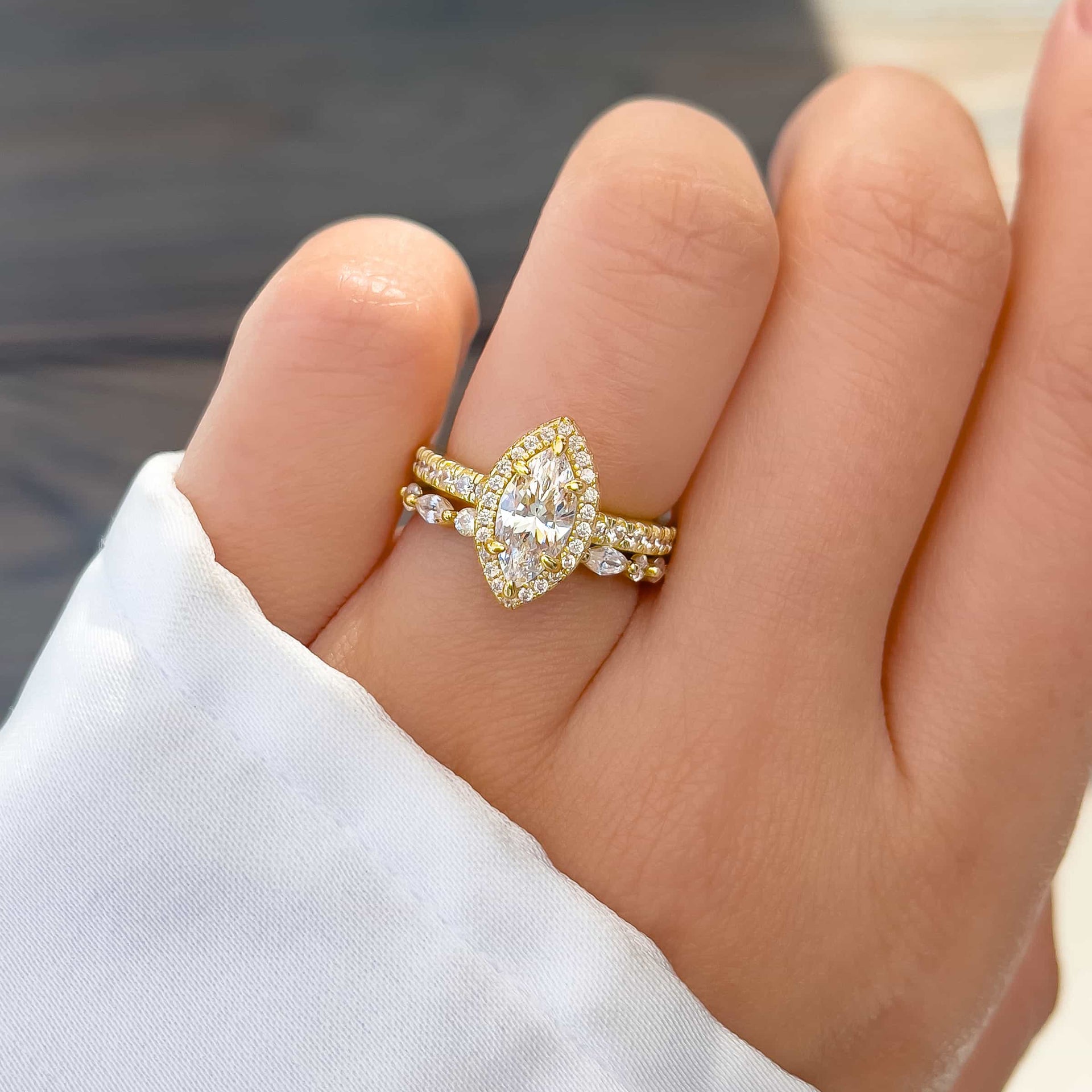 vintage style wedding ring set made up of 1 carat marquise cut engagement ring and unique gold wedding band on model with white sleeve