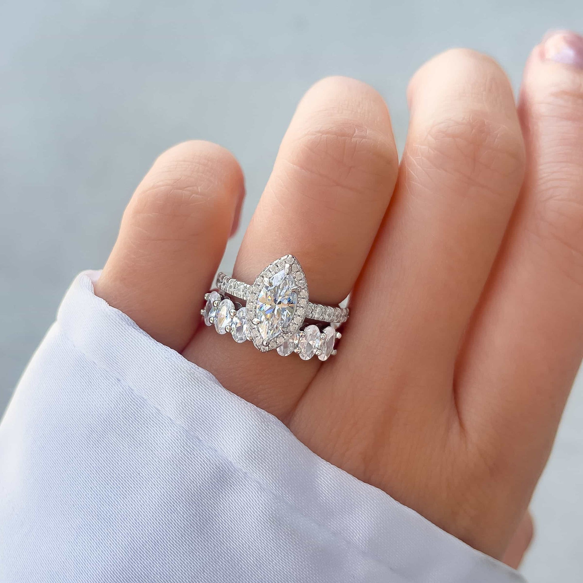 vintage style wedding ring set made up of 1 carat marquise cut engagement ring and a bold, silver wedding band on model with white sleeve