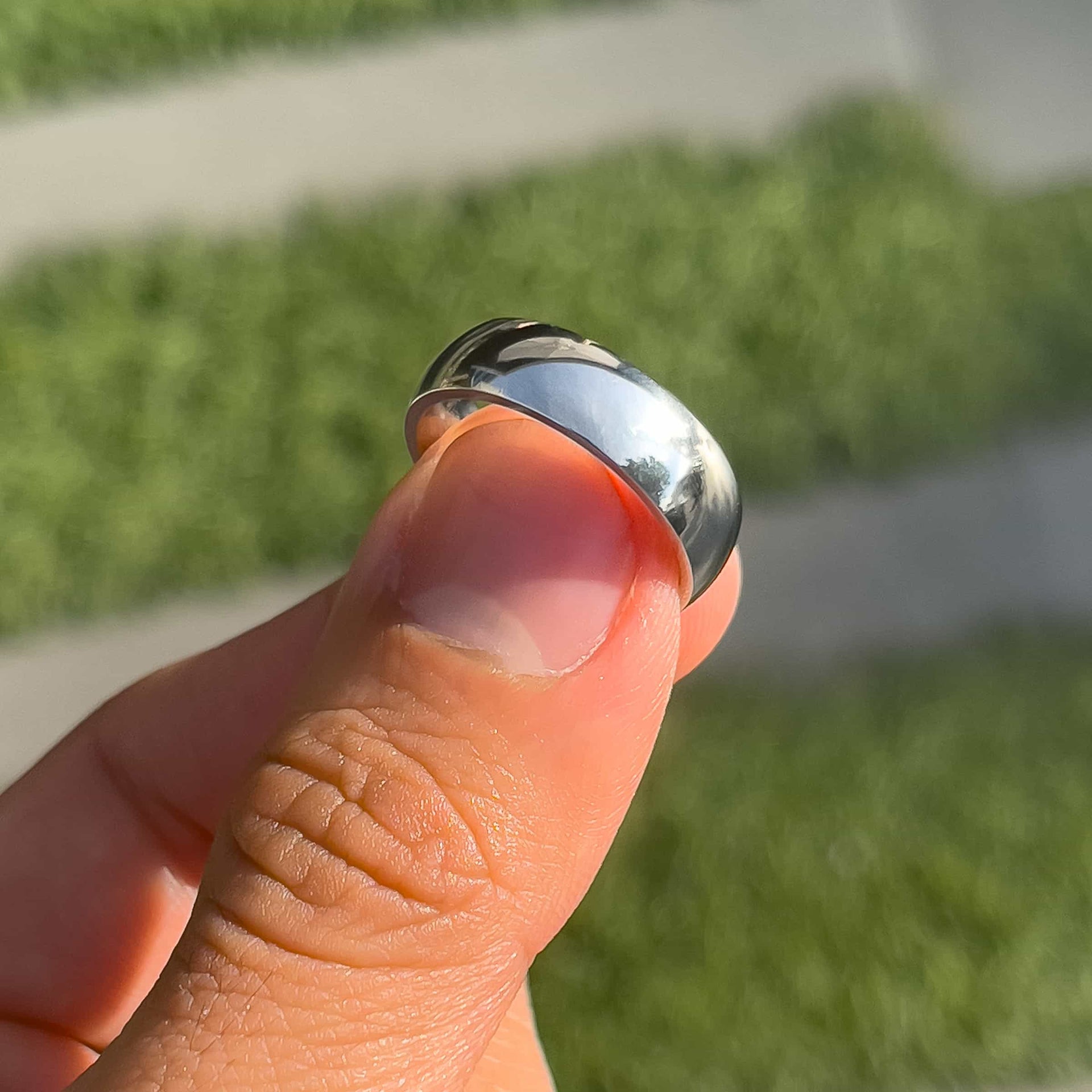 affordable silver mens Horizon wedding ring shown on model's thumb with greenery in the background