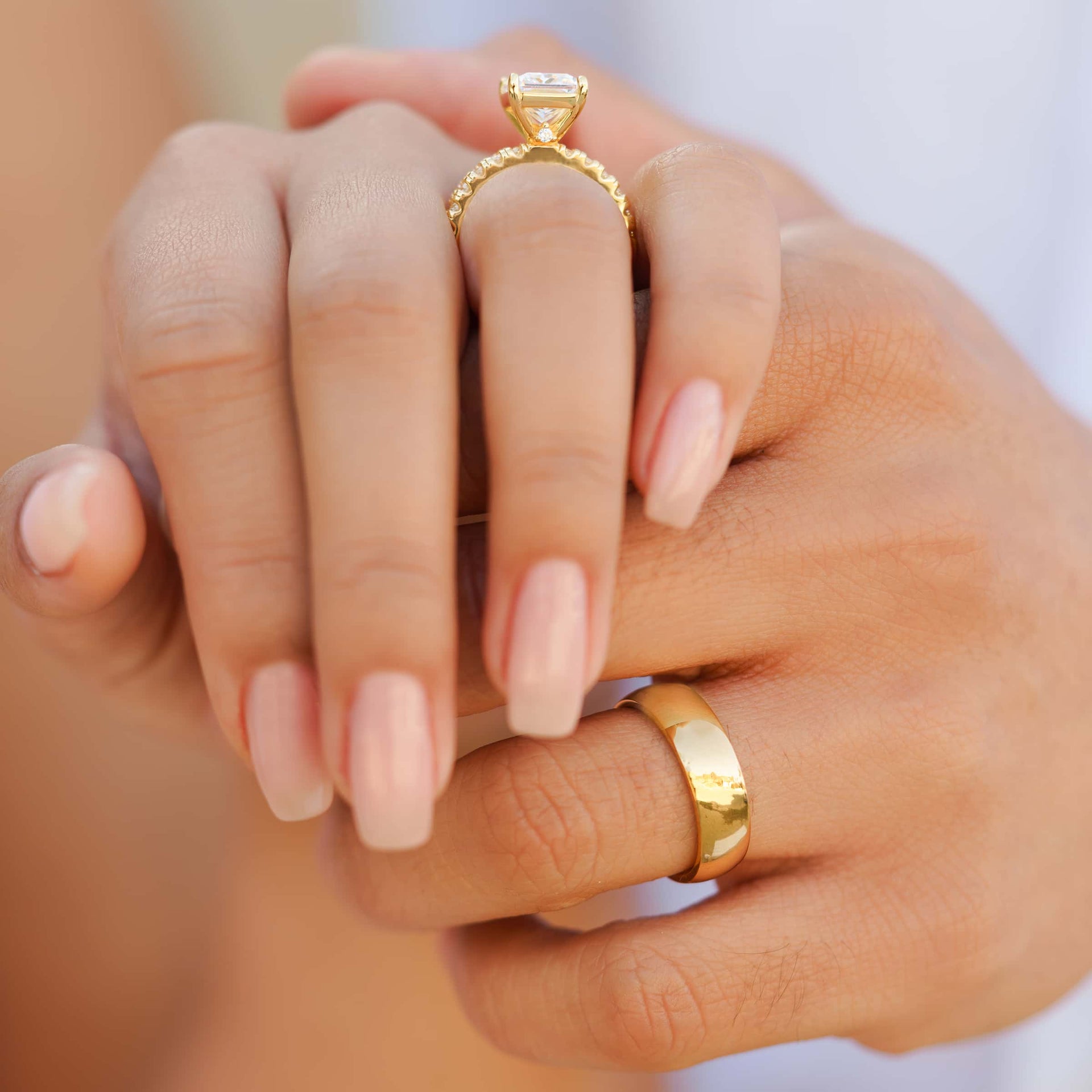 stunning women's gold engagement ring setting shot shown with men's gold wedding ring on couple's hand 