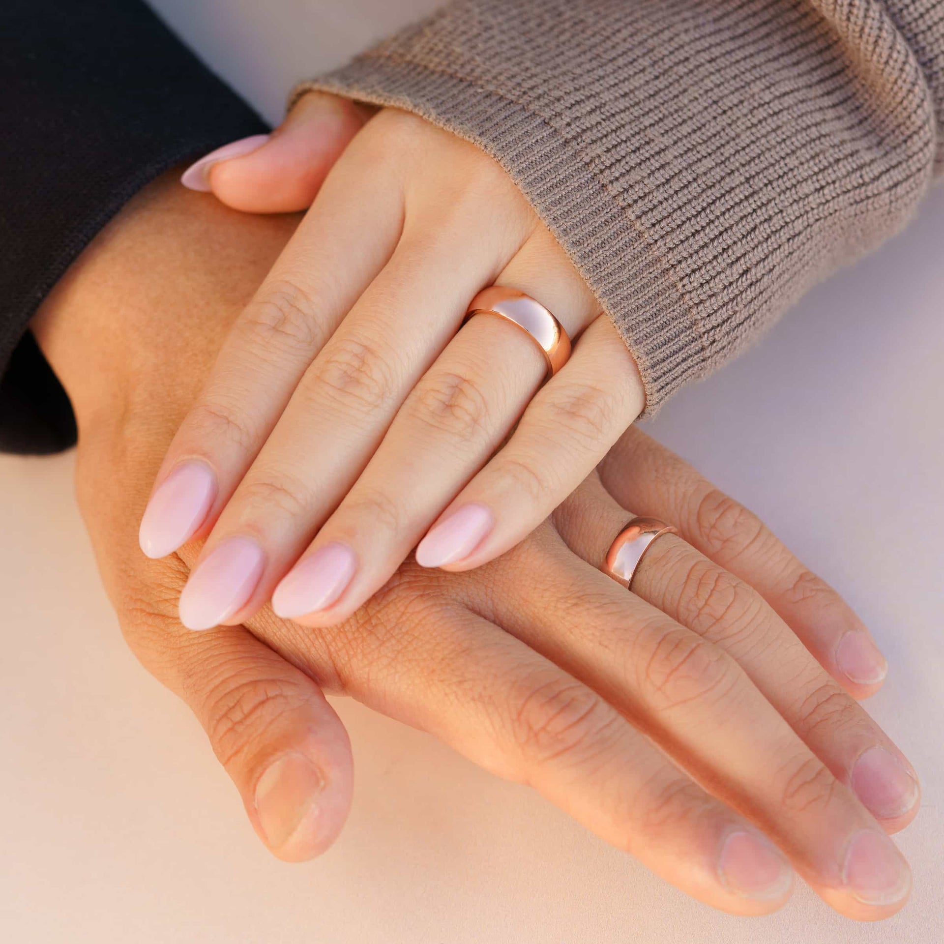 affordable unisex rose gold Horizon wedding bands shown on hands of couple 