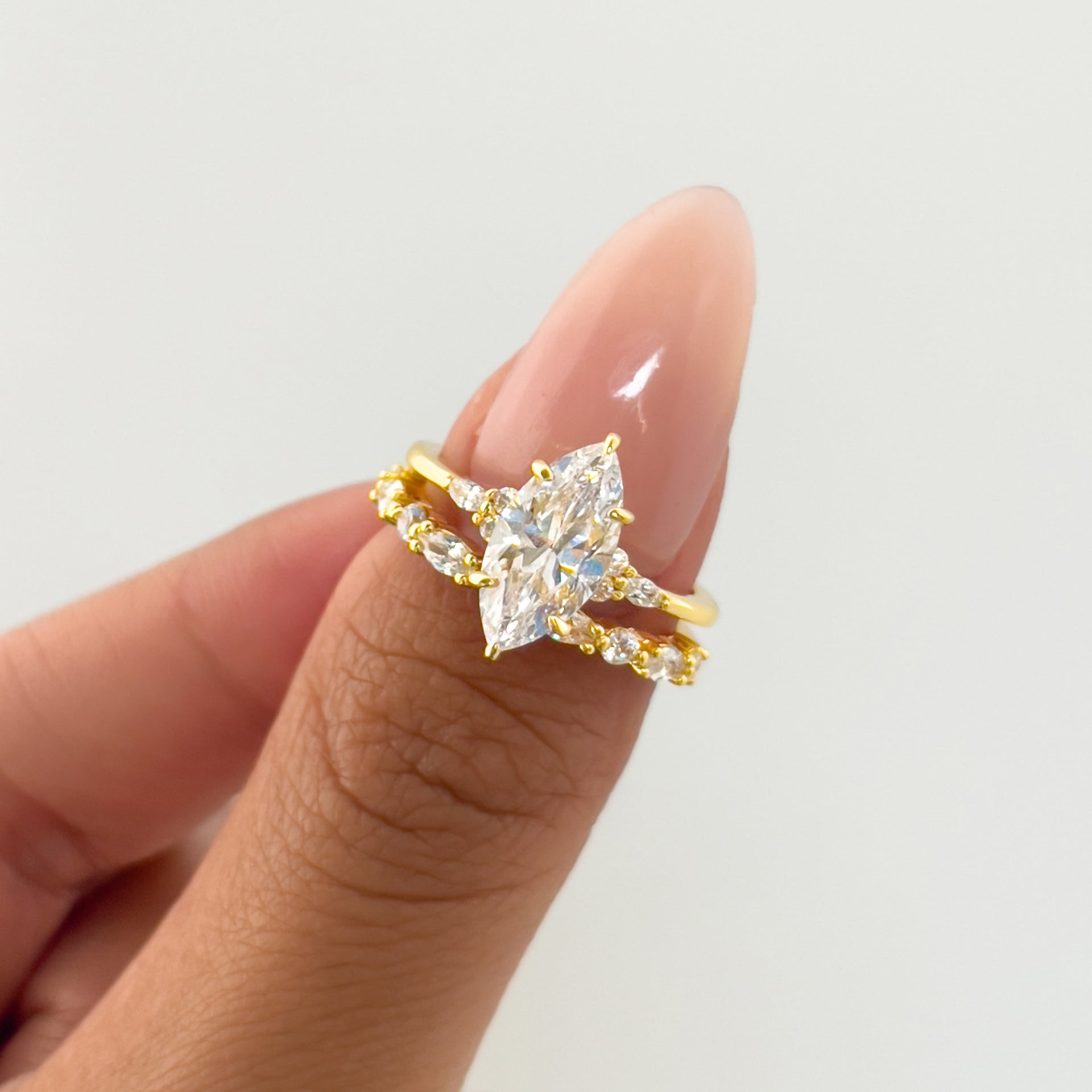unique gold wedding set made up of marquise cut engagement ring and a vintage half eternity wedding band on model with neutral nails