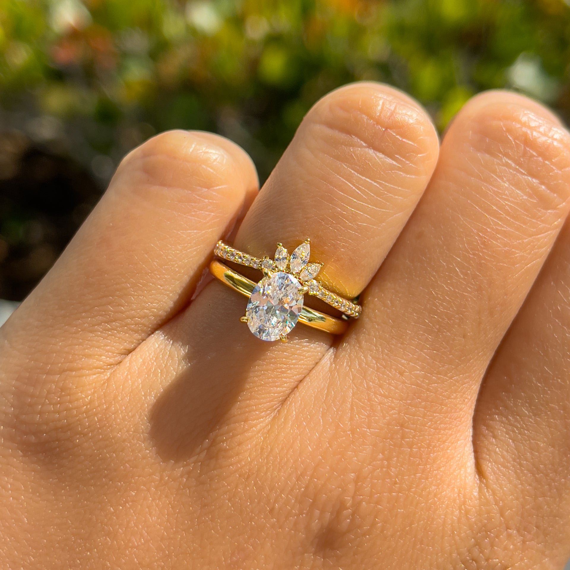 Gold petite oval solitaire engagement ring paired with a gold vintage wedding band on female model