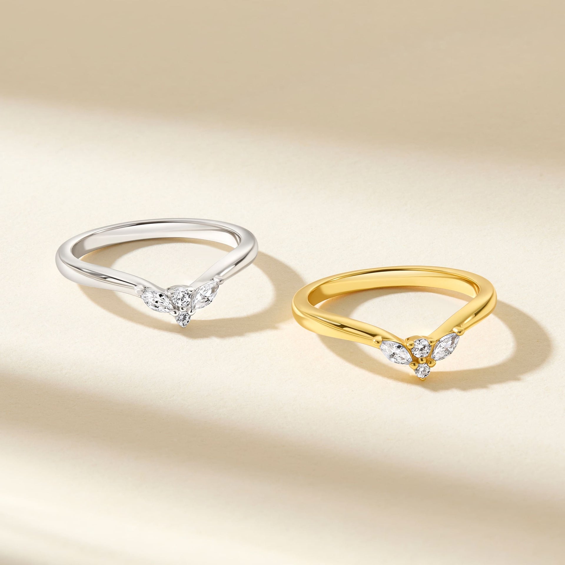 simple, sleek vintage chevron wedding bands shown in silver and gold on a tan, neutral background