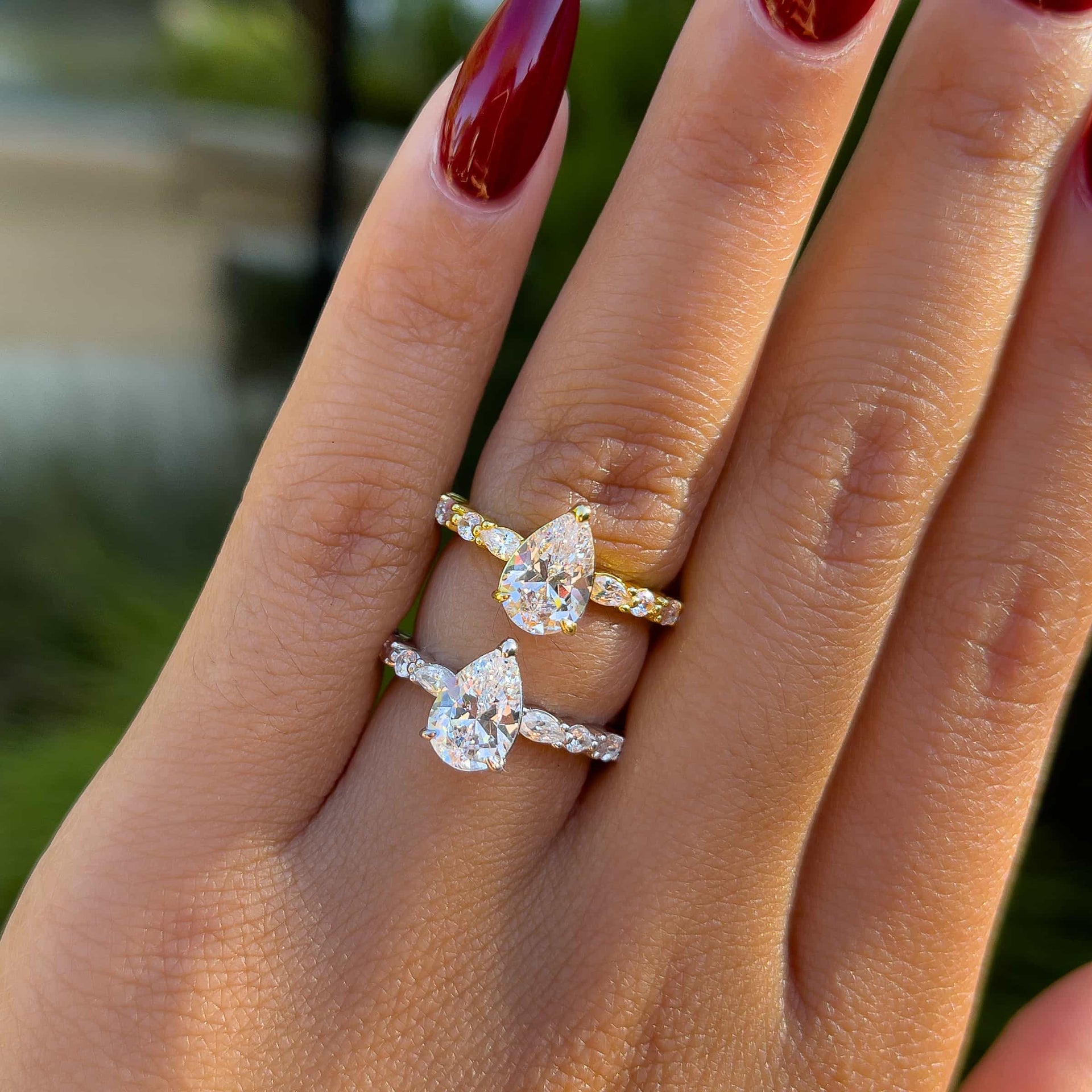 gorgeous 1.5 carat pear cut vintage engagement ring shown in gold and silver on a model with deep red nails