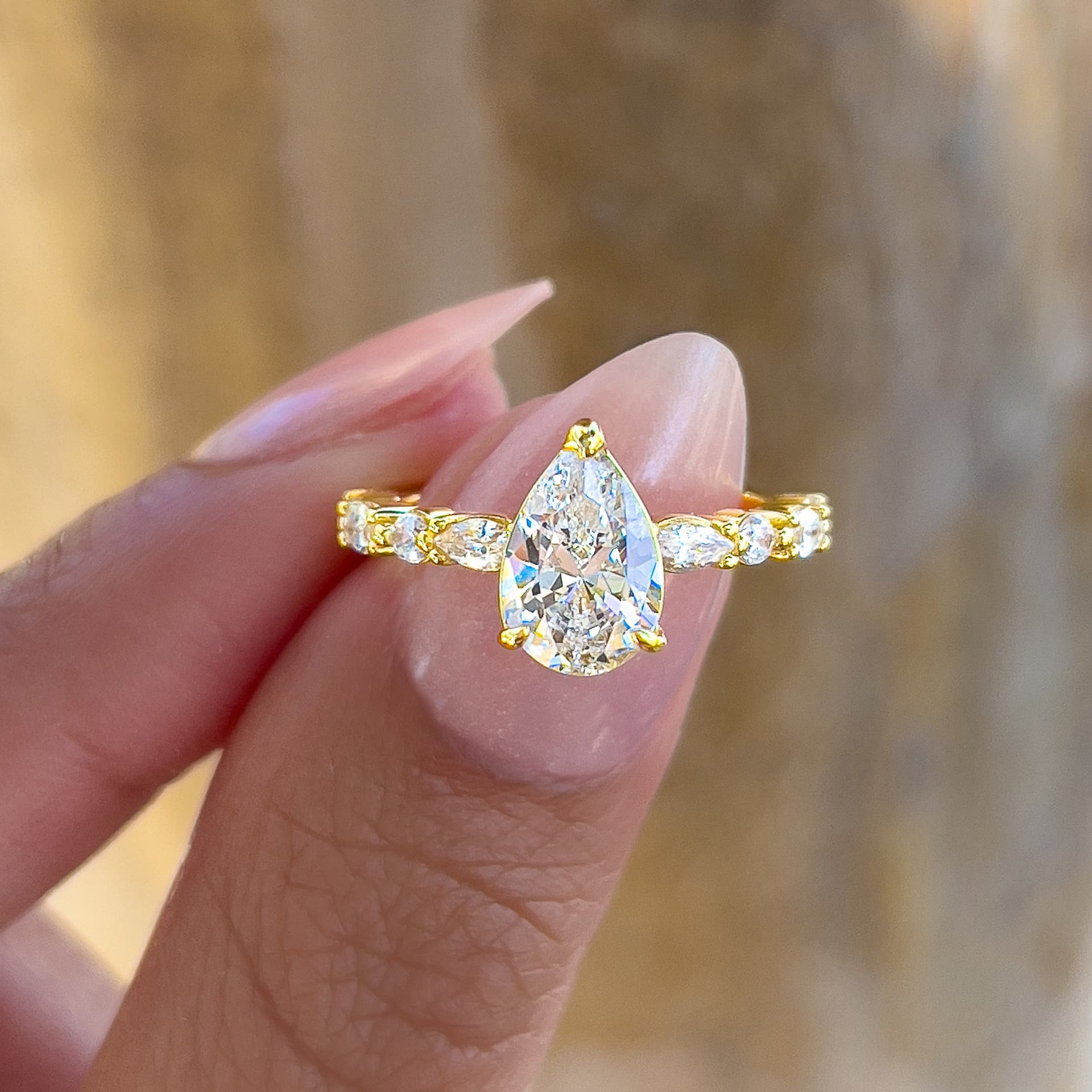stunning 1.5 carat vintage pear cut half eternity ring held by model with light pink nails