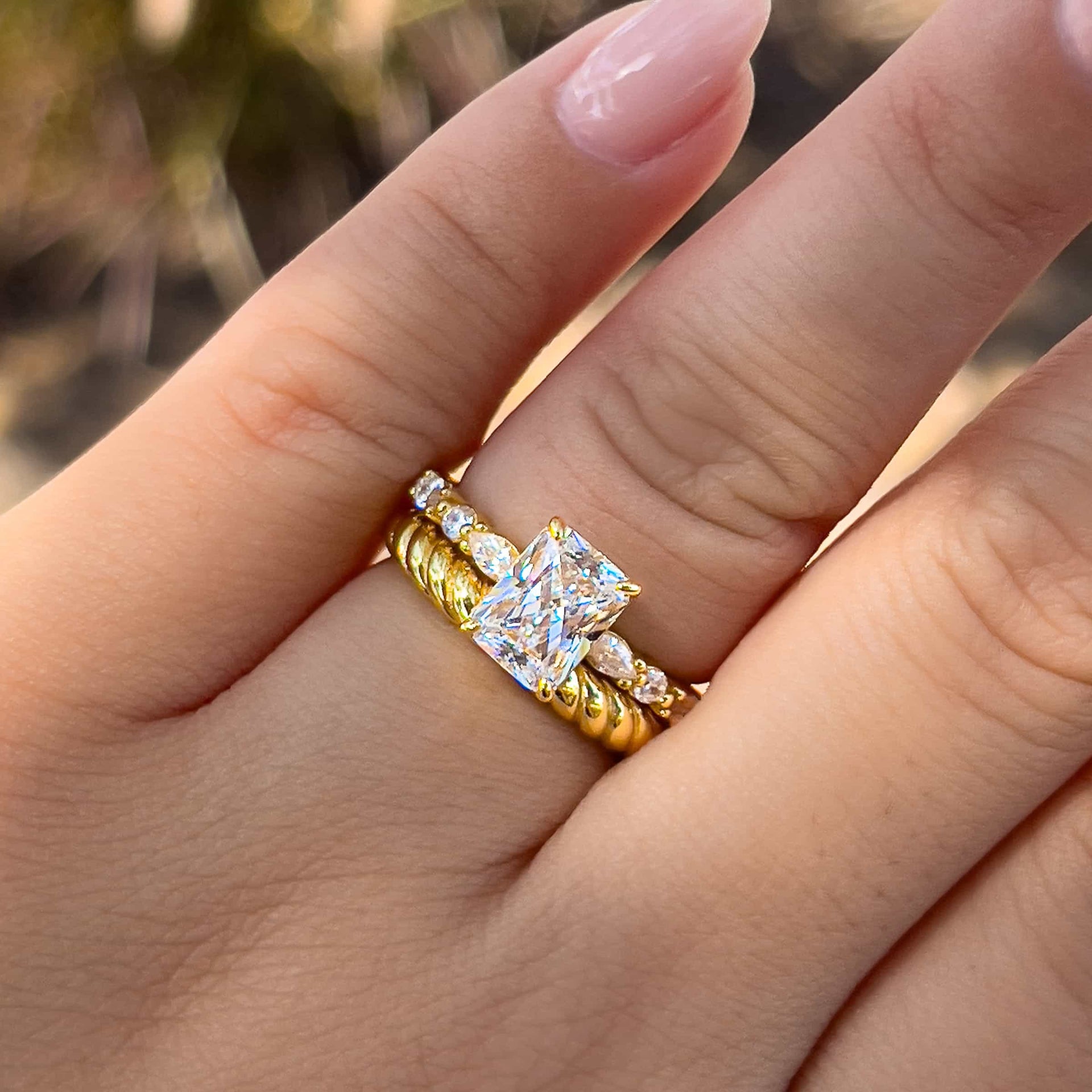 unique gold radiant cut wedding ring set on model with neutral nails