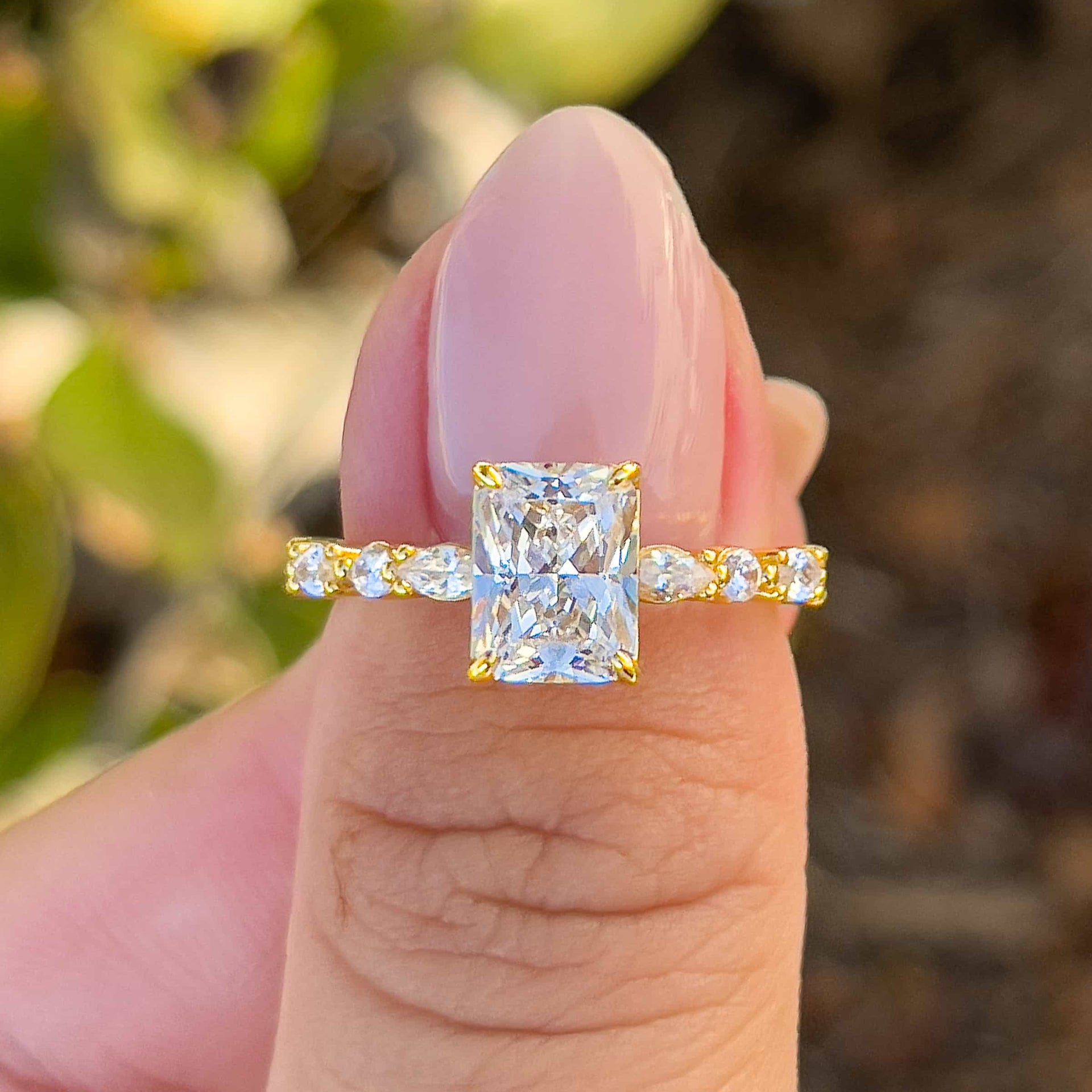 stunning 2 carat vintage radiant cut half eternity ring held by model with pink nails