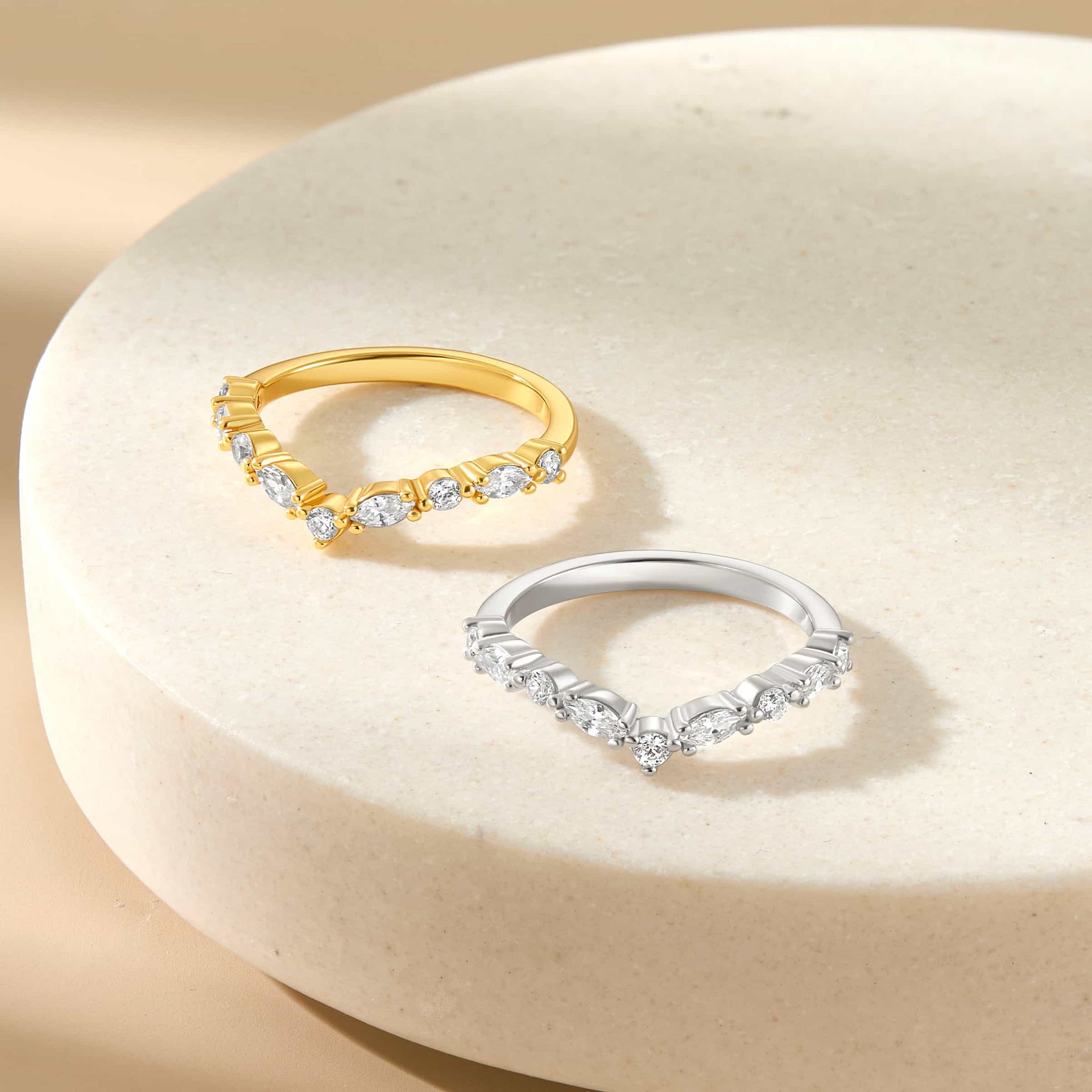 vintage style half eternity chevron band shown in gold and silver on a stone-like background