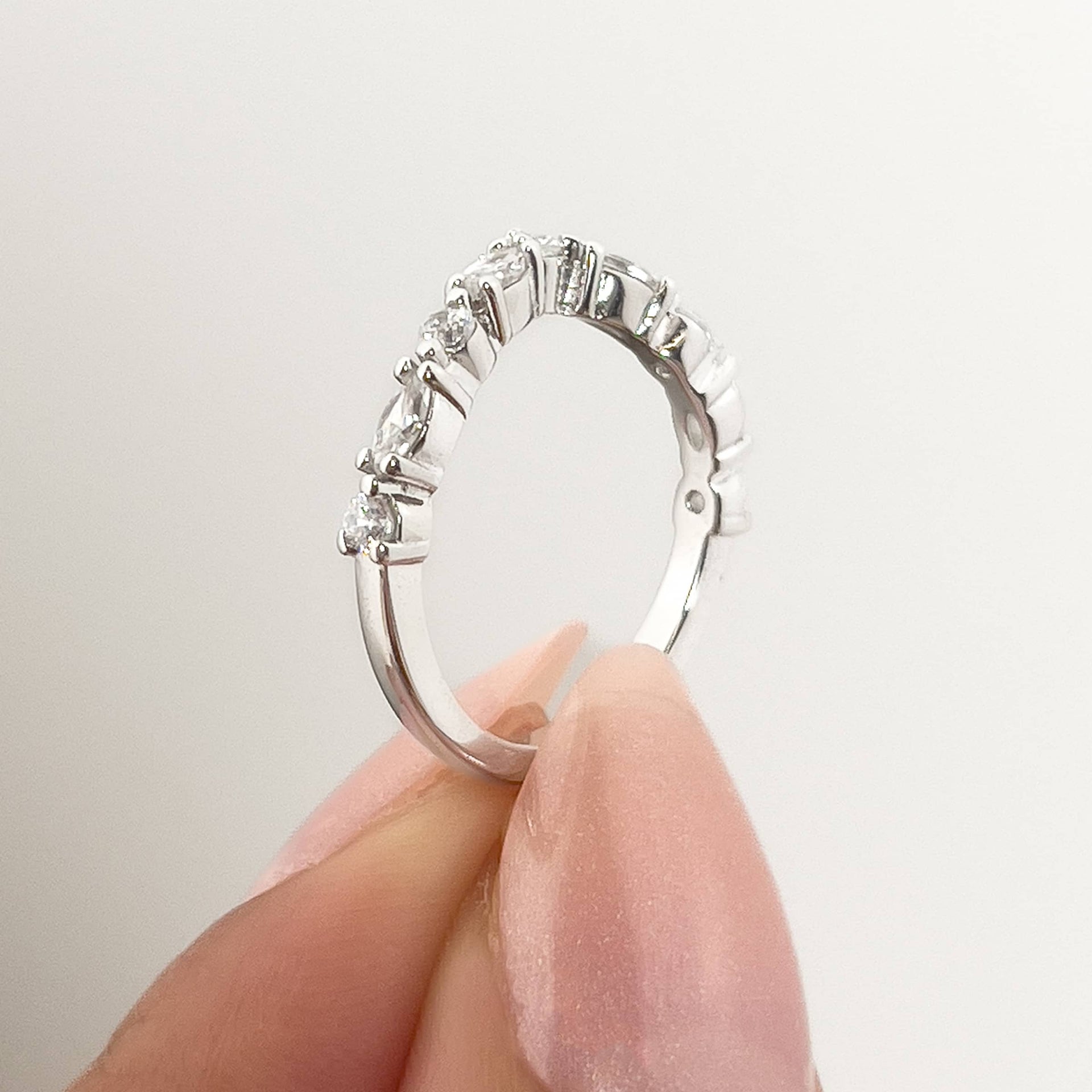 setting shot of a vintage chevron half eternity band held by model with neutral nails