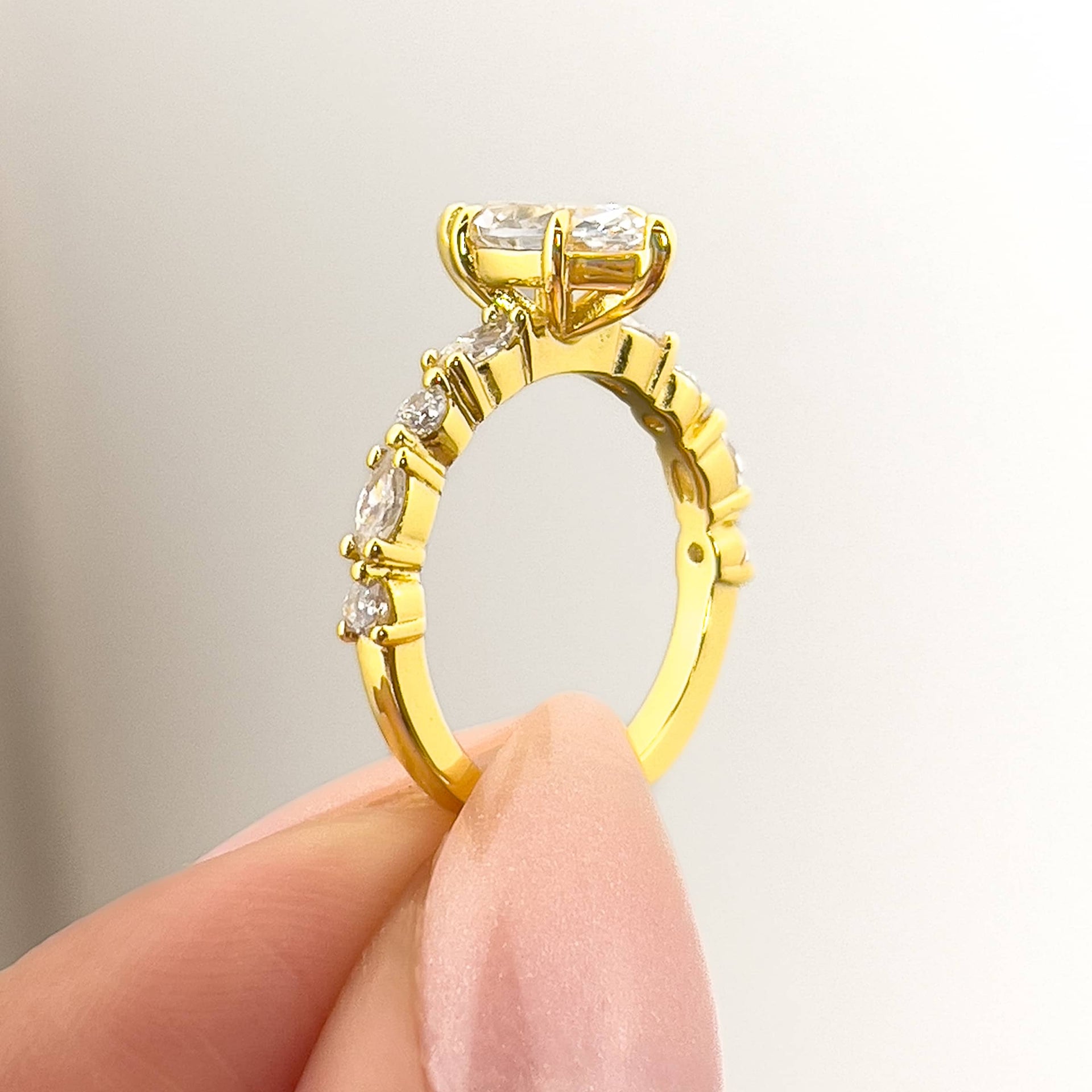 setting shot of a vintage style 1 carat marquise cut engagement ring held by model with neutral nails