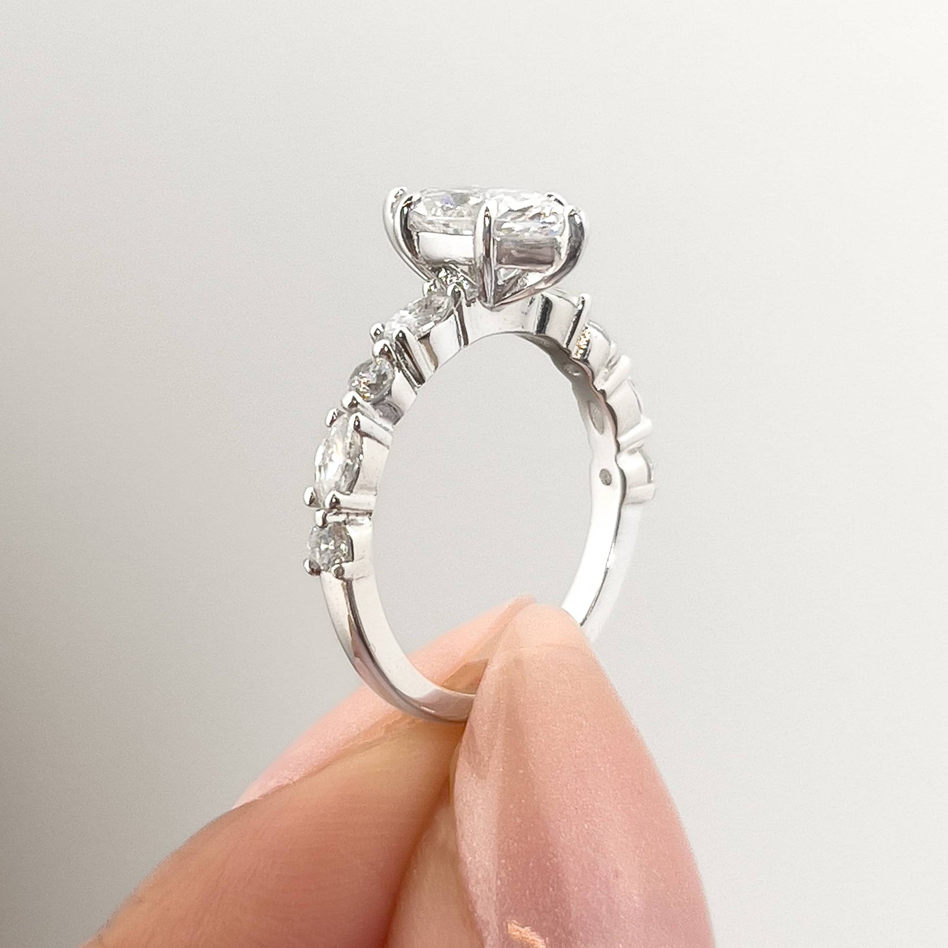 setting shot of a vintage style 1 carat marquise cut engagement ring held by model with neutral nails