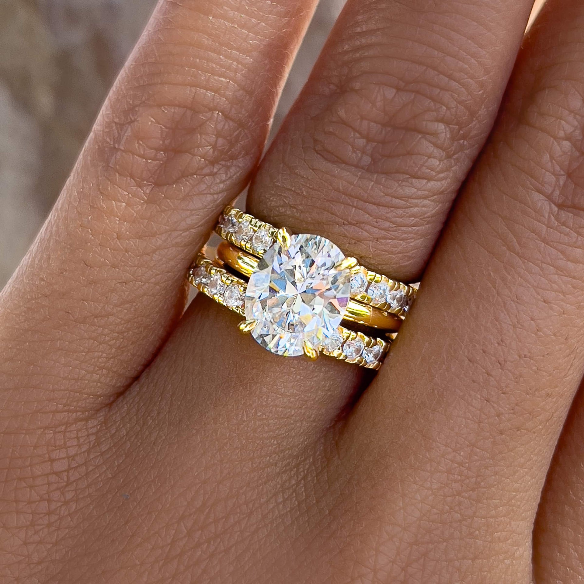 gold oval cut wedding ring set paired with a 2nd full eternity band to create a triple ring stack worn by female model