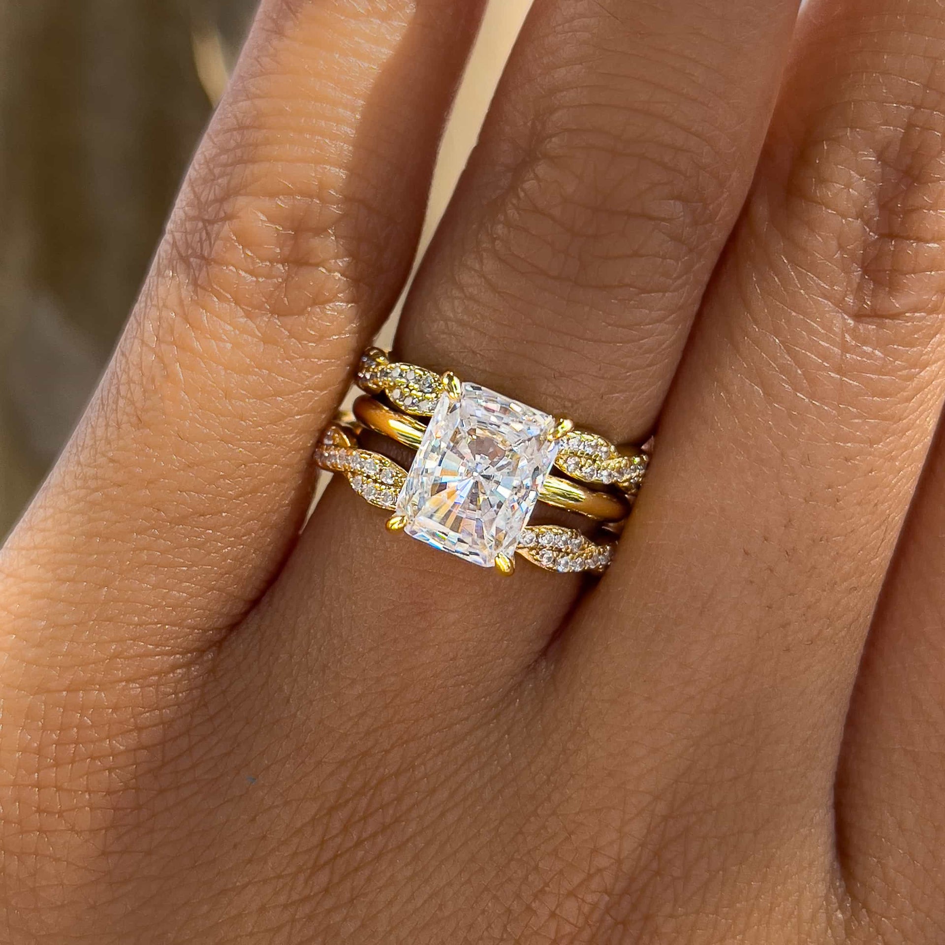gold radiant cut wedding ring set paired with a 2nd full twisted eternity band to create a triple ring stack worn by female model