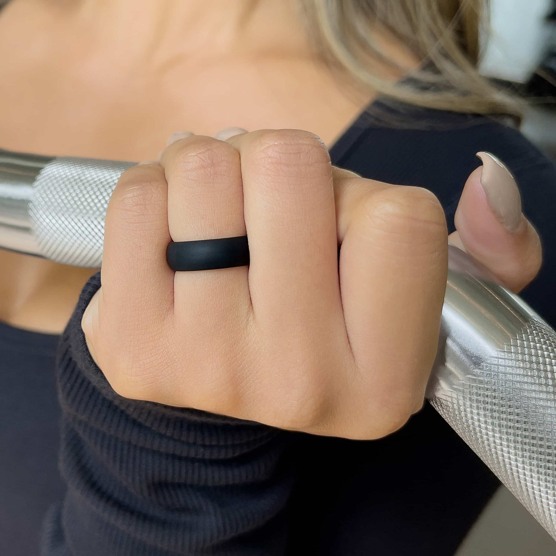 comfortable black silicone alternative band worn by model with neutral nails in a gym setting