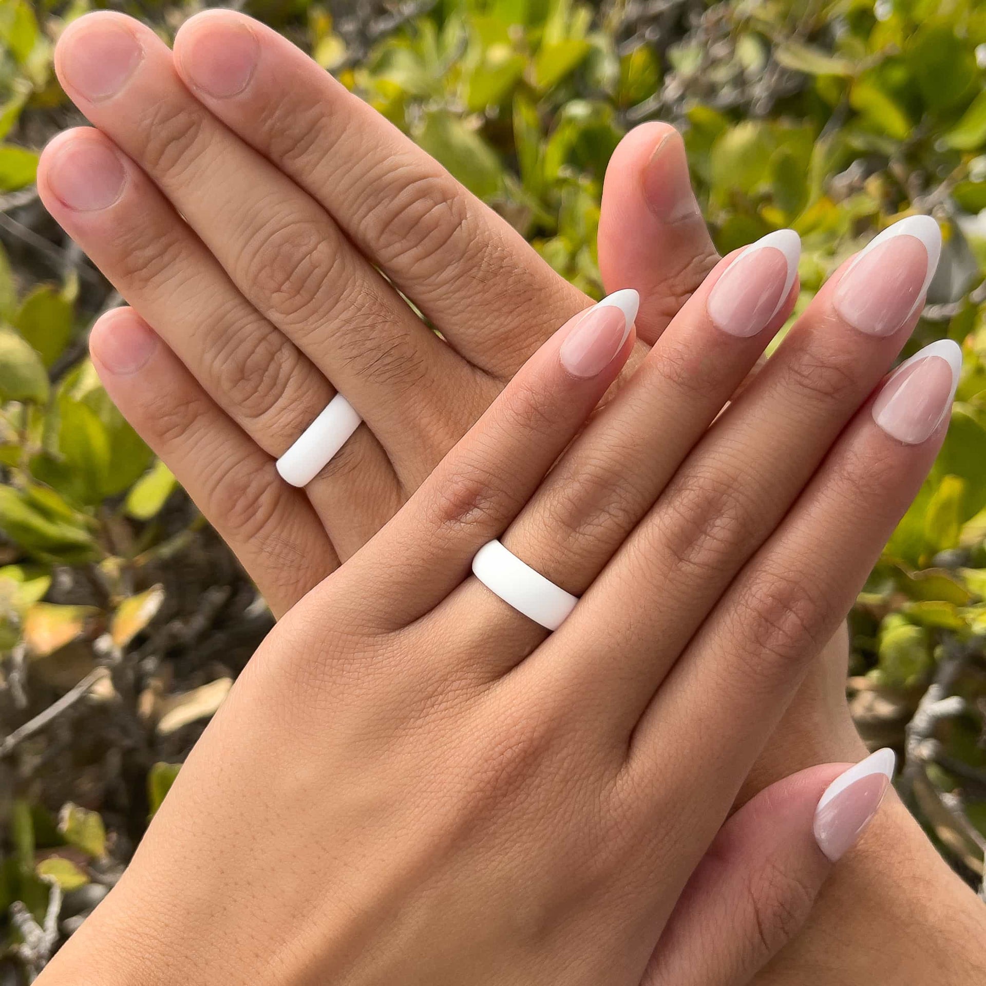 unisex white silicone band worn by both a male and female model in front of greenery