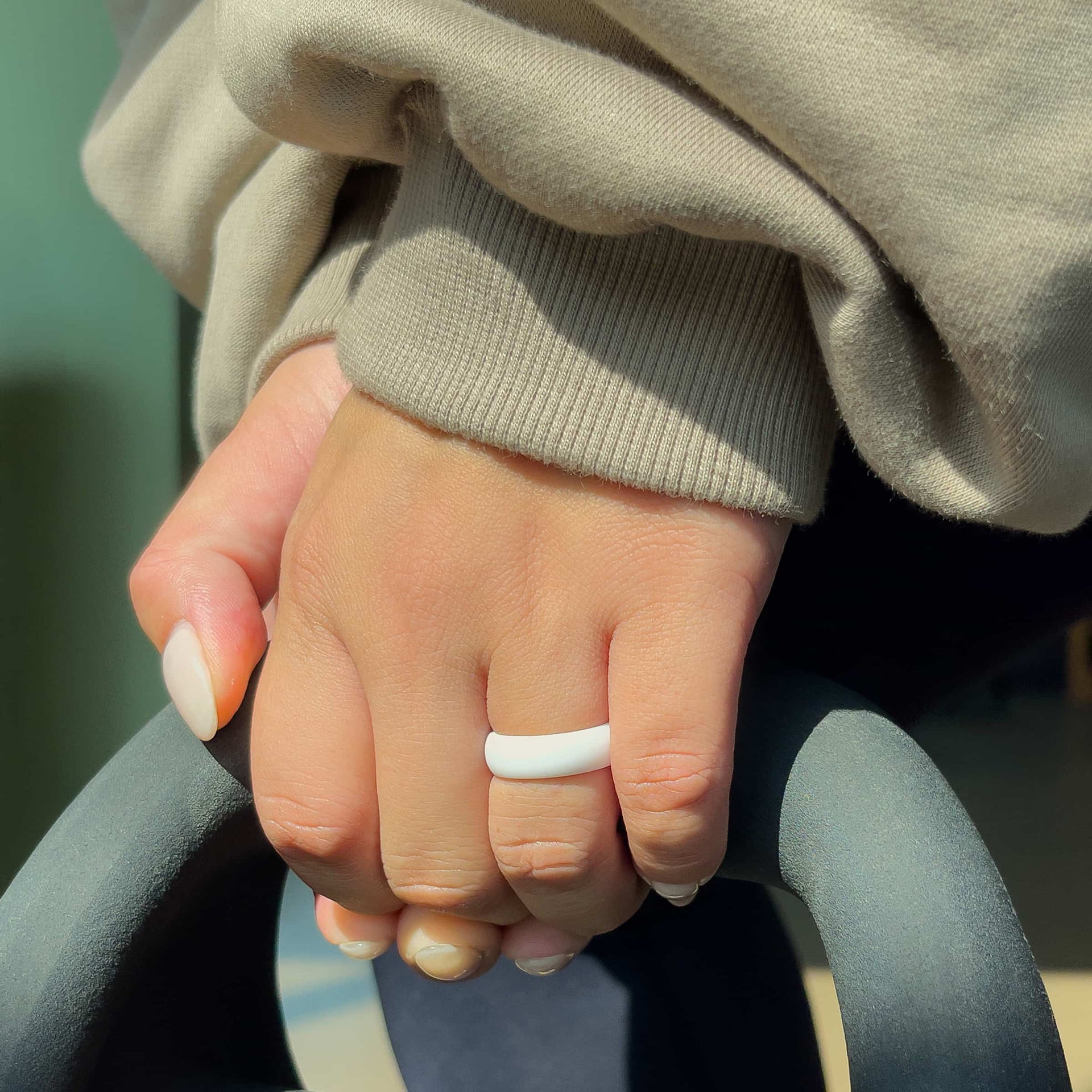 white silicone alternative band worn by model with neutral nails in a gym setting