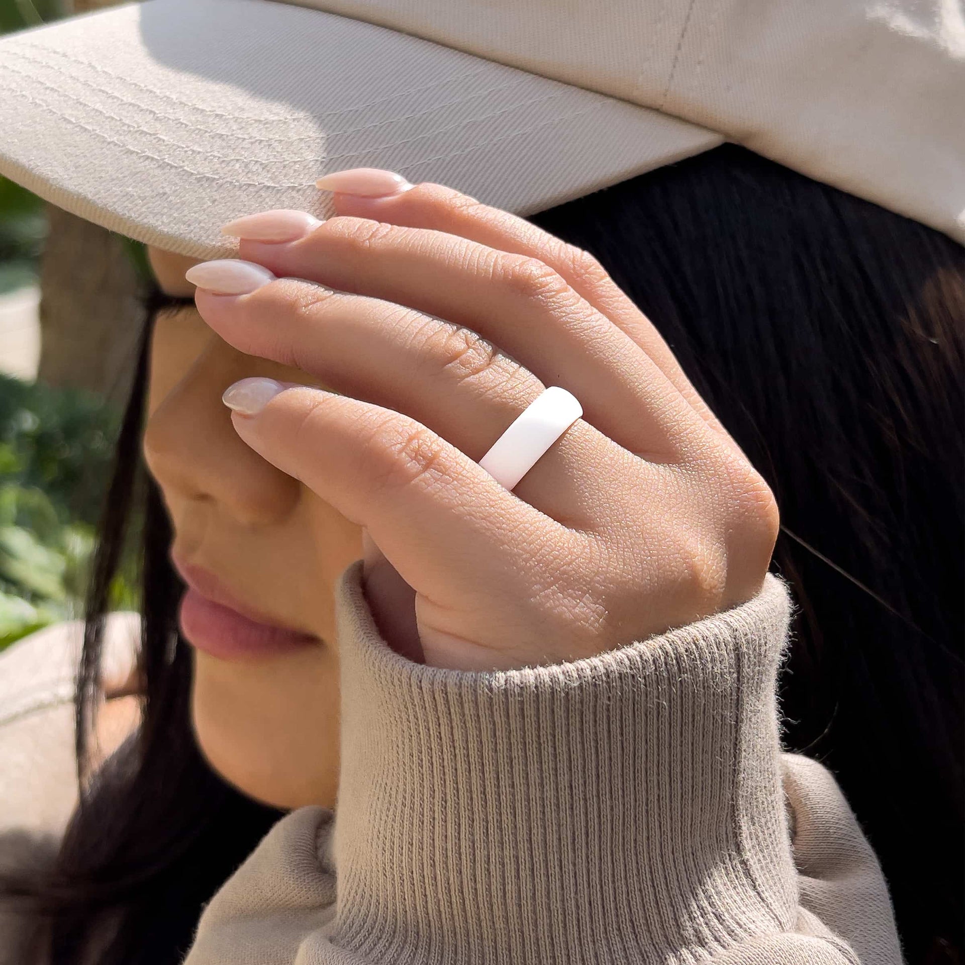 versatile white silicone band worn by model with neutral nails and hat
