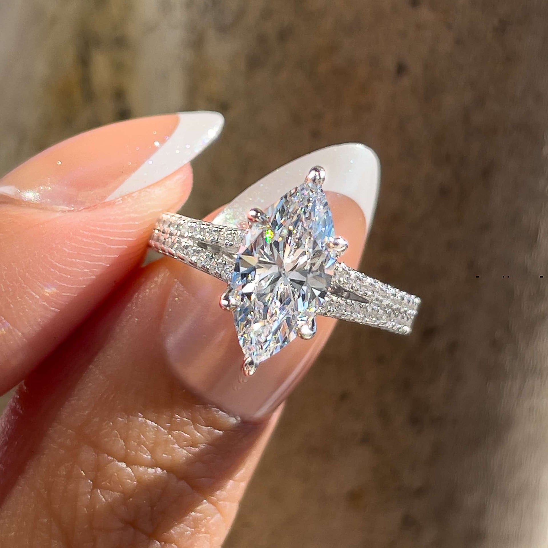 Vintage style 2 carat marquise cut split shank engagement ring held by model with french tip nails