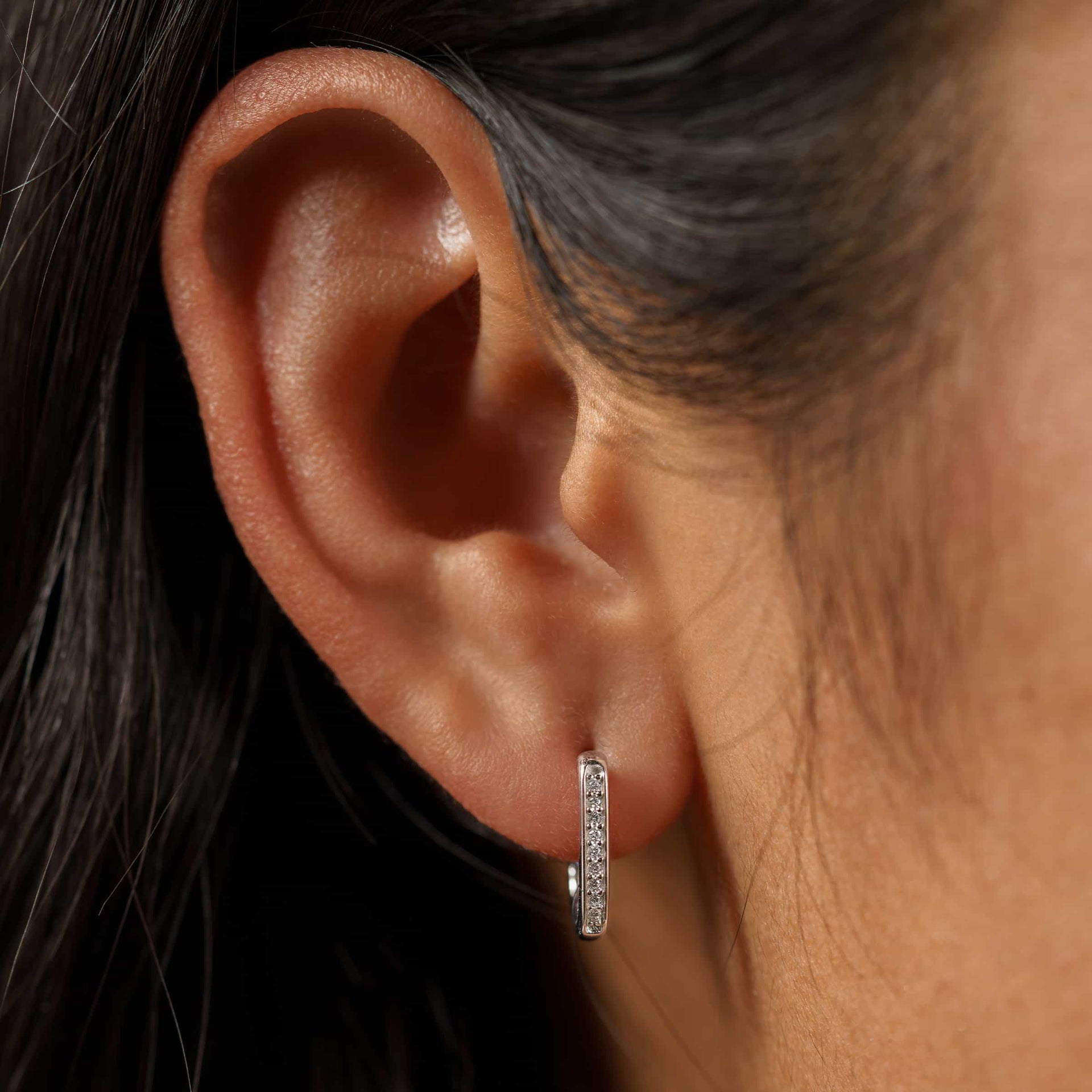 small silver square/rounded hoop style earrings with stones on model with dark hair
