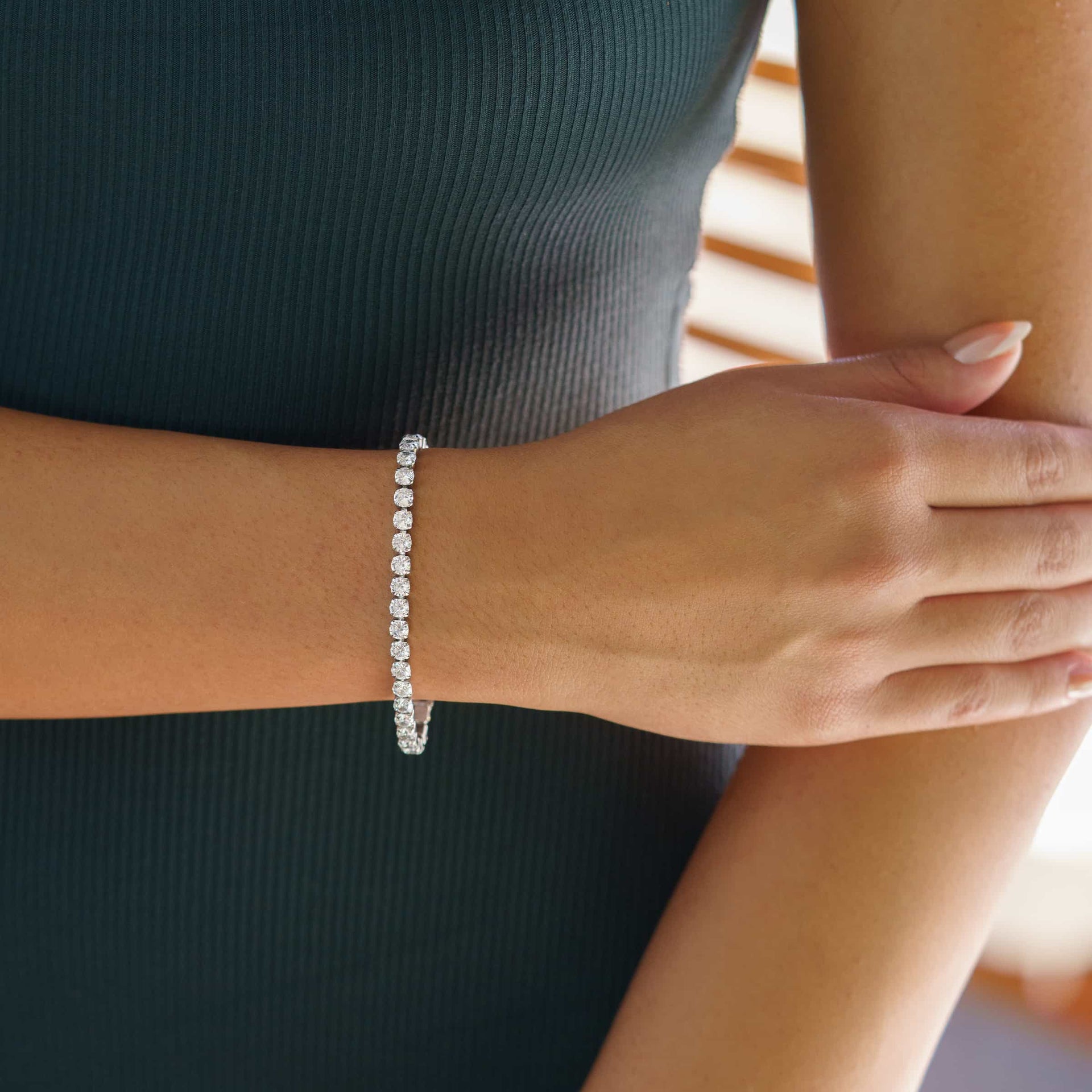 gorgeous silver tennis bracelet on model wearing dark colored dress