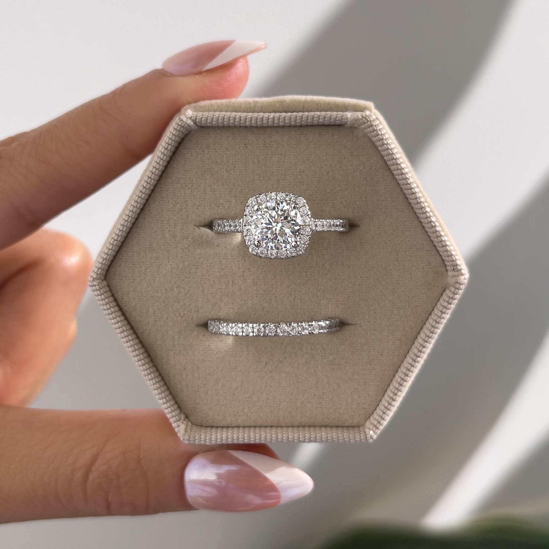stunning silver wedding set inside a stone velvet hexagon box held by model with french tip nails
