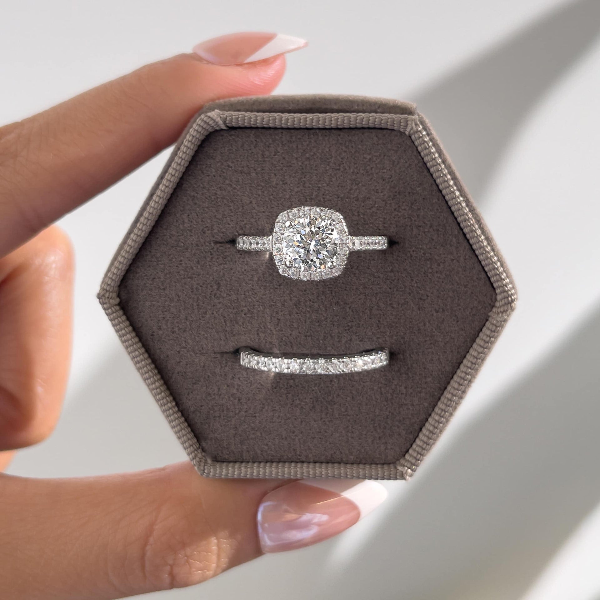 stunning silver wedding set inside a taupe velvet hexagon box held by model with french tip nails