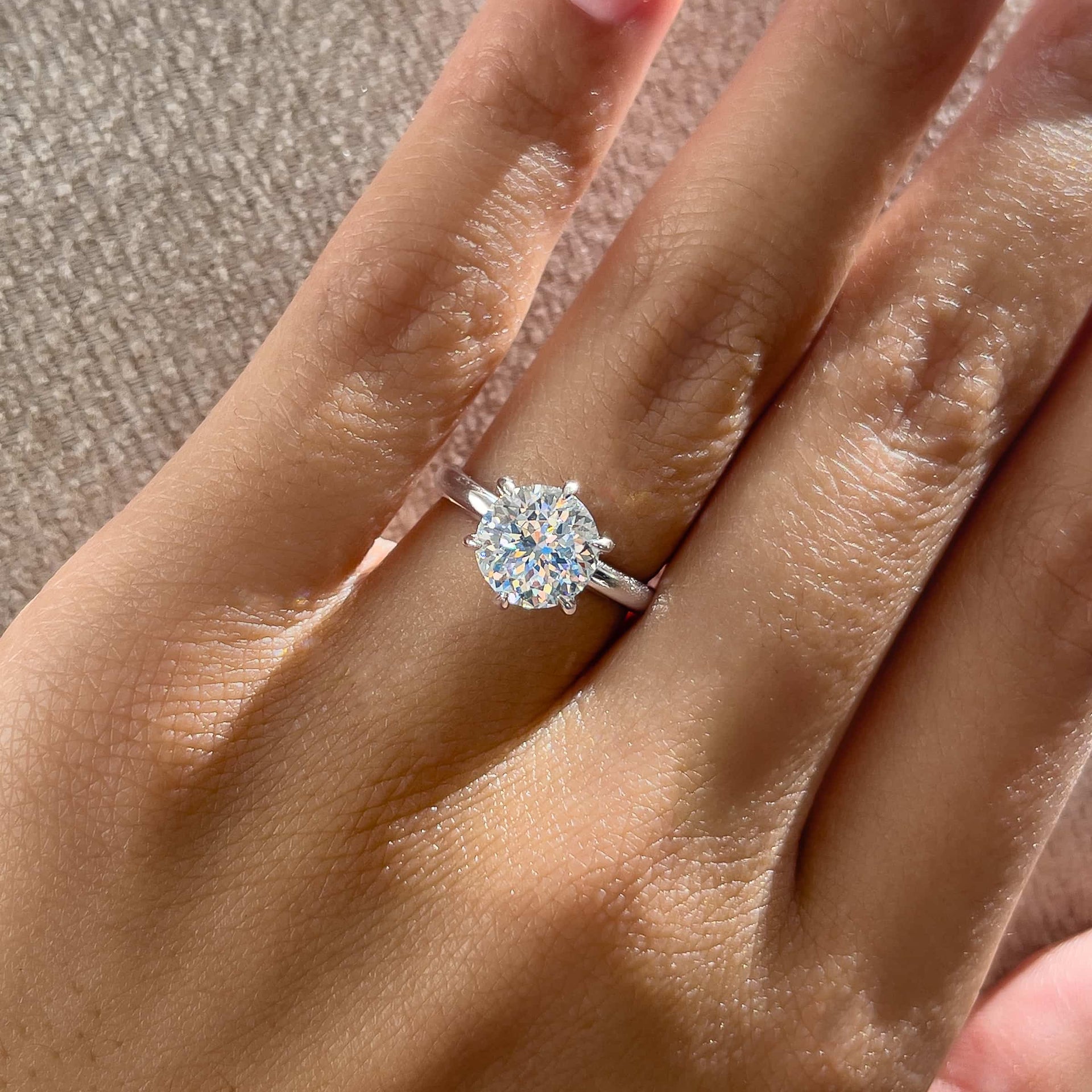 close up of silver round cut solitaire ring on model