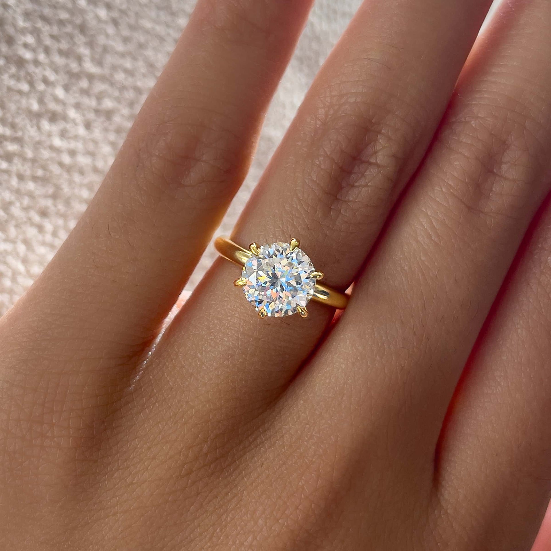 Close up of gold round cut solitaire ring on model