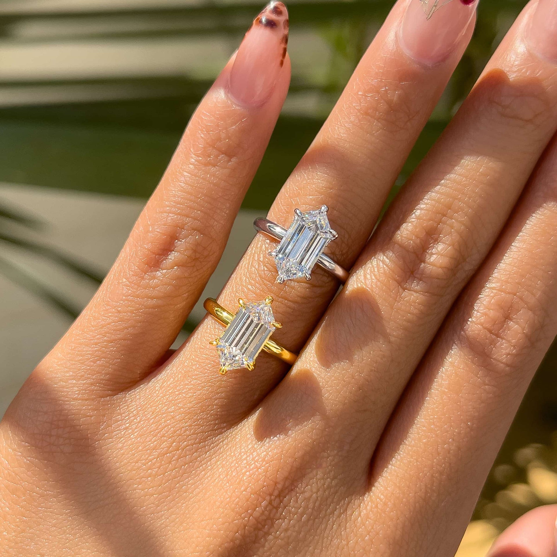 a 2.5 carat hexagon cut solitaire engagement ring shown in silver and gold, both on a model with unique french tip nails