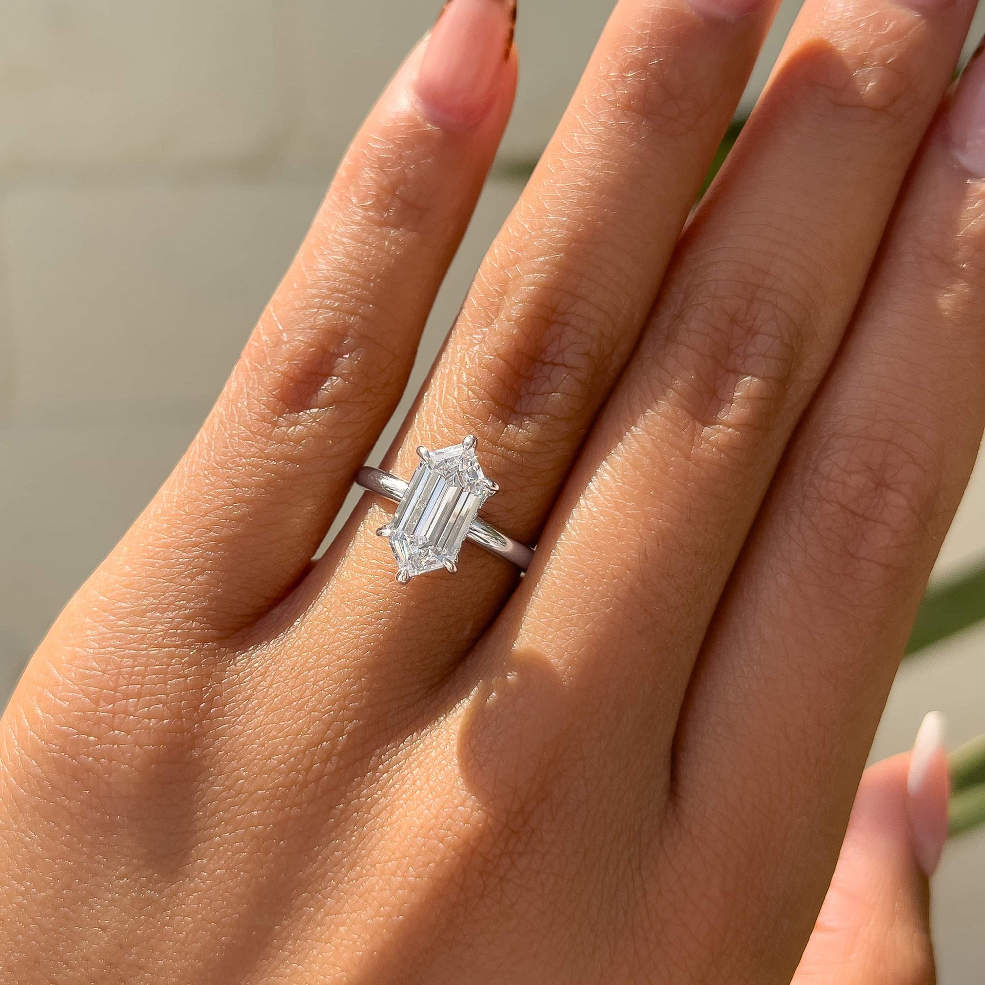 a simple, yet unique silver 2.5 carat hexagon cut, 6 prong solitaire engagement ring worn by a model