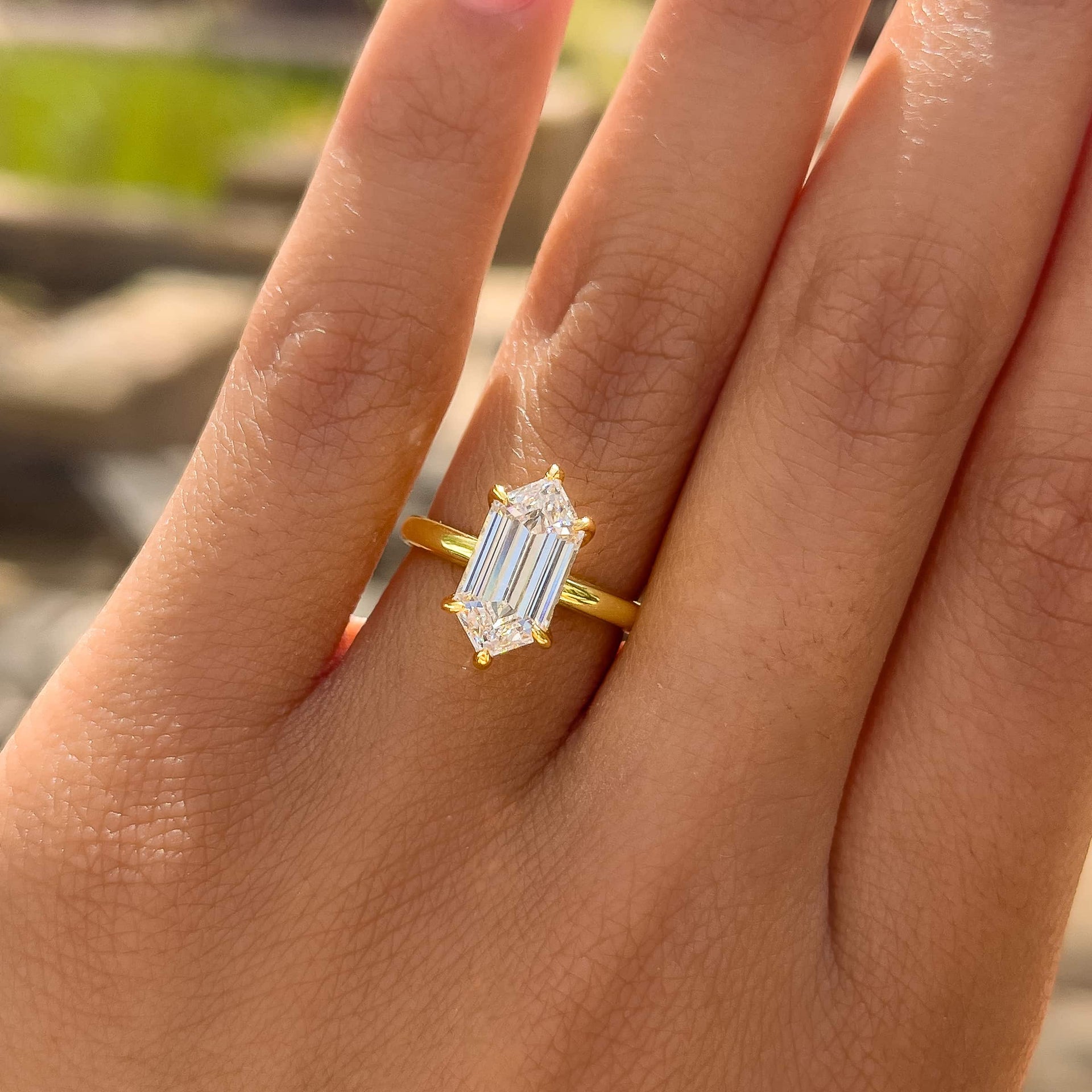 a simple, yet unique gold 2.5 carat hexagon cut, 6 prong solitaire engagement ring worn by a model