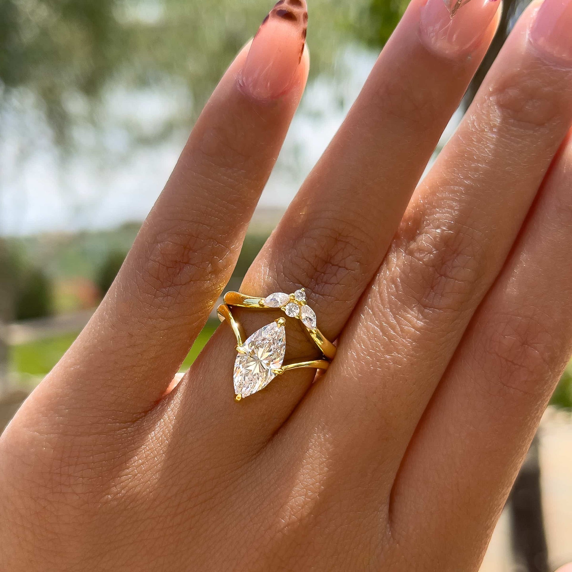 gold 2 carat marquise solitaire chevron engagement ring paired with a vintage wedding band worn by a model with unique nails