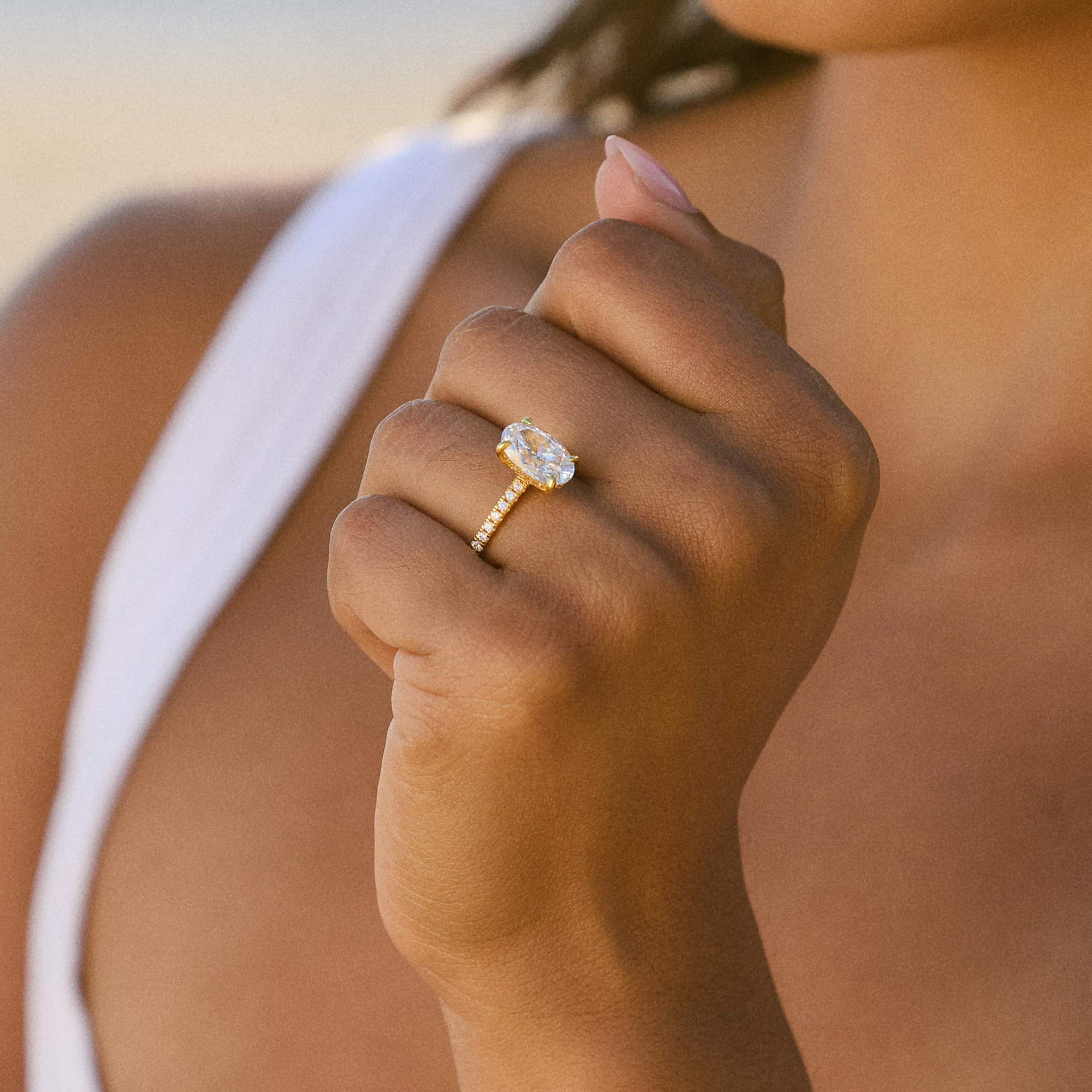 gold 4 carat oval cut half eternity engagement ring worn by model in white top