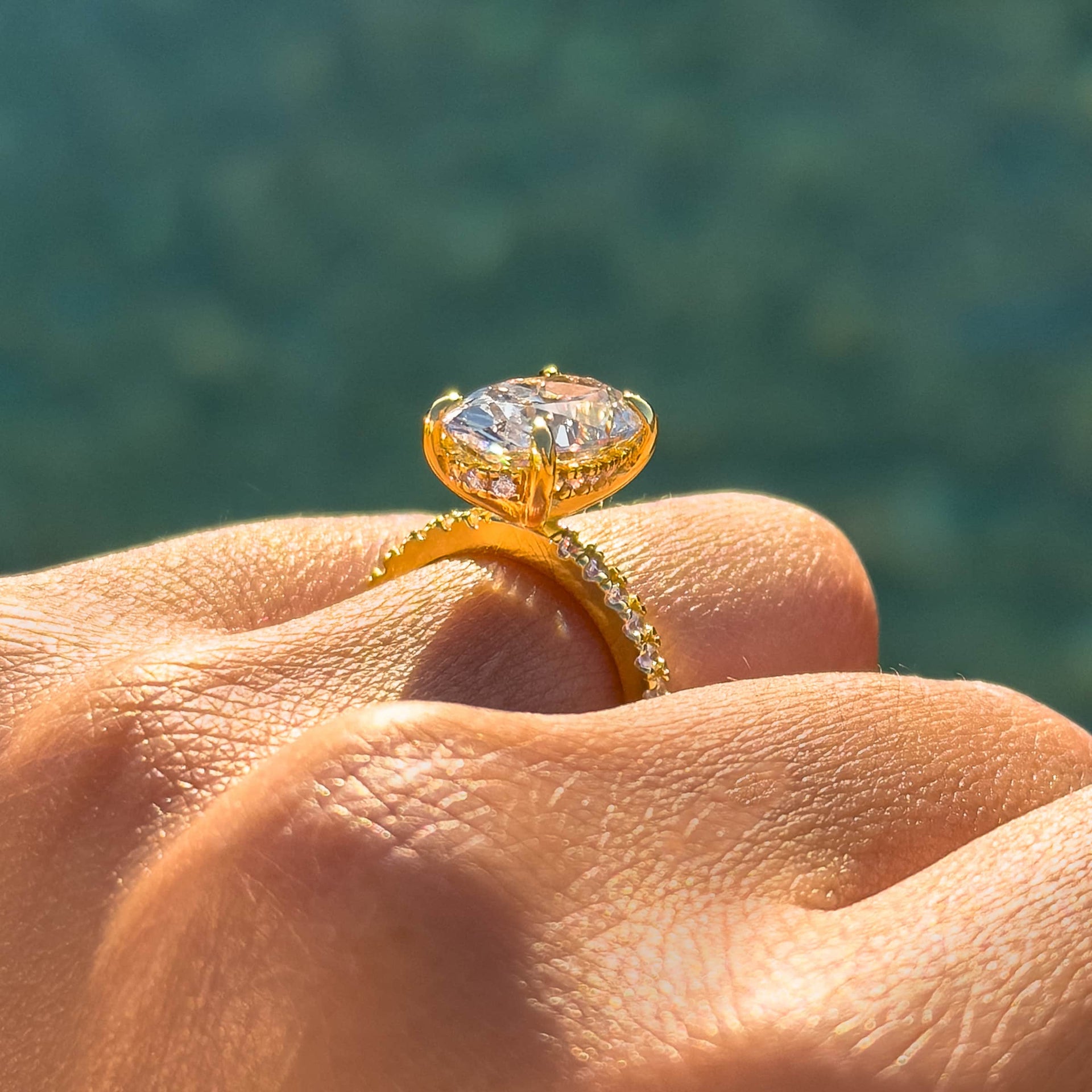 gold 4 carat oval cut half eternity engagement ring with hidden halo shown from a side view while worn by model