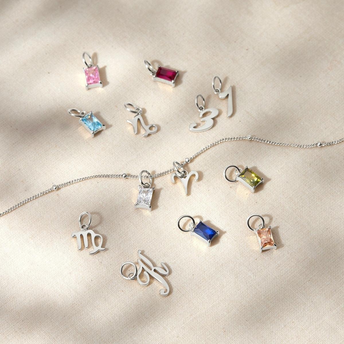 a variety of dainty charms posed across a tan surface 