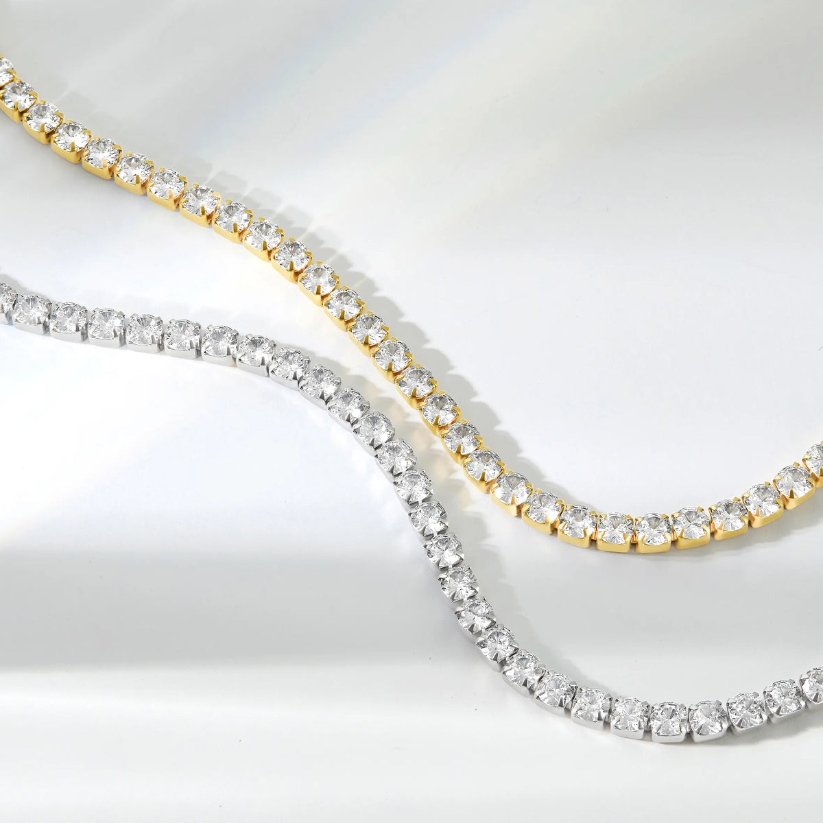 surgical grade 316 stainless steel tennis bracelets unclasped in a natural position shown in gold and silver on a white background