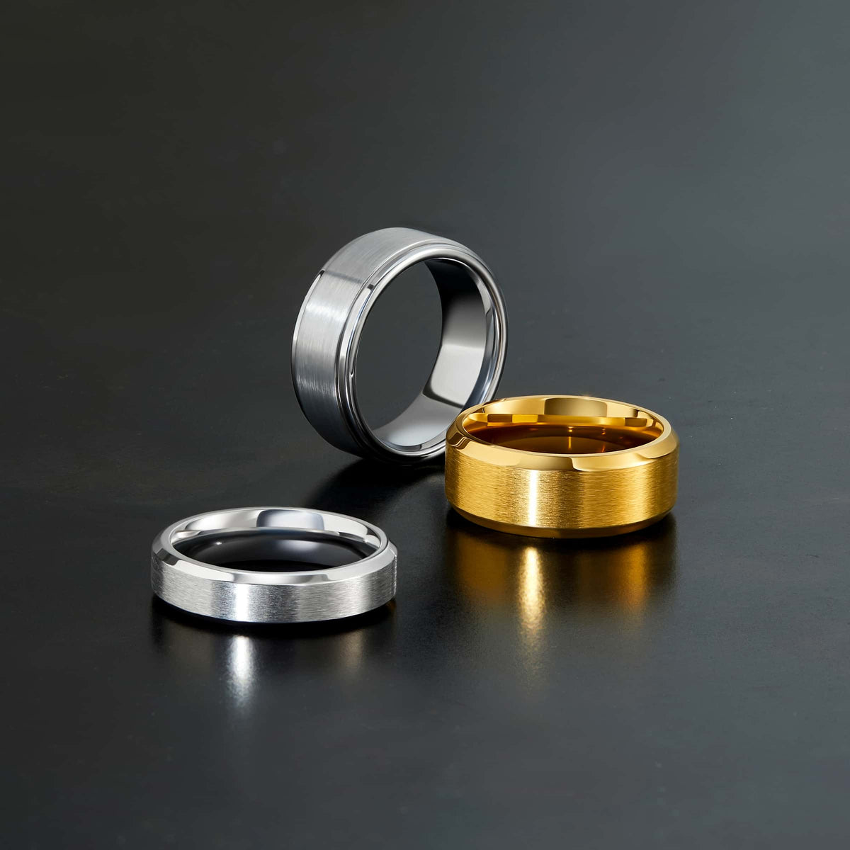 a variety of tungsten carbide and stainless steel bands on a dark background