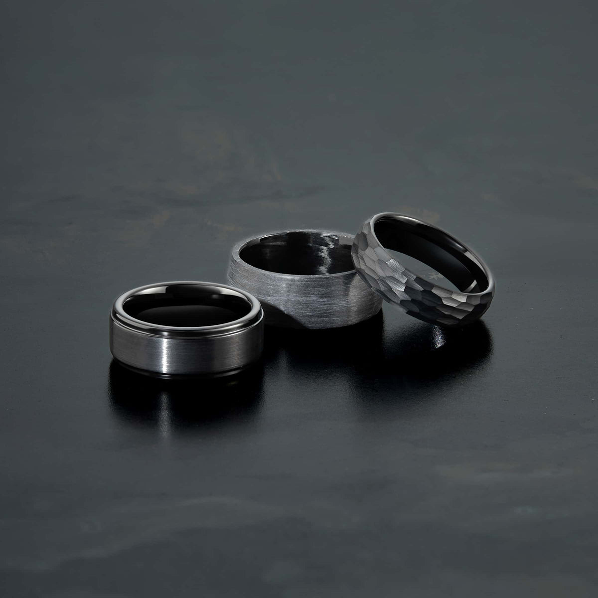 a variety of black tungsten carbide wedding bands on a dark background