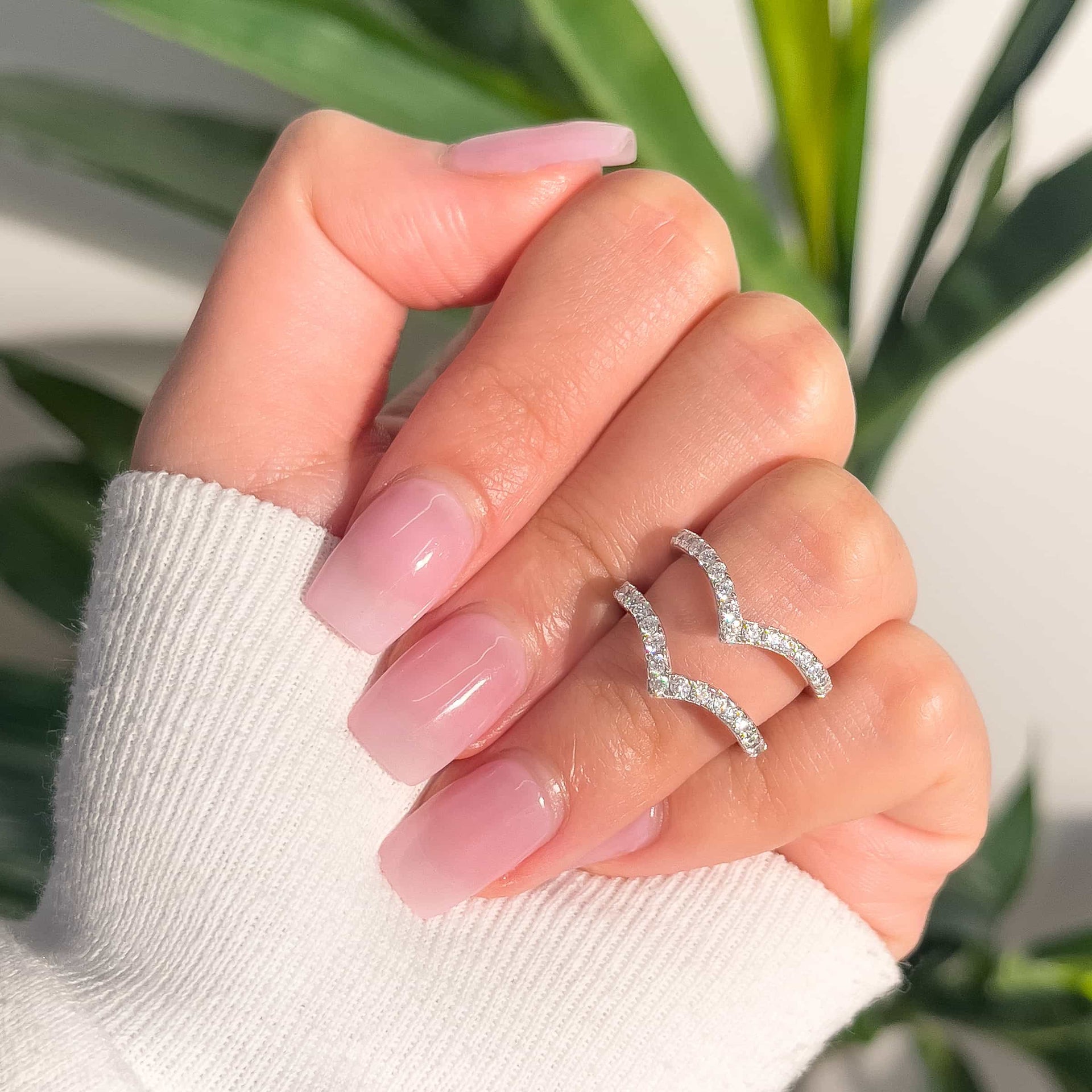 silver half eternity chevron wedding band set of two on female hand with natural pink nails and white sweater