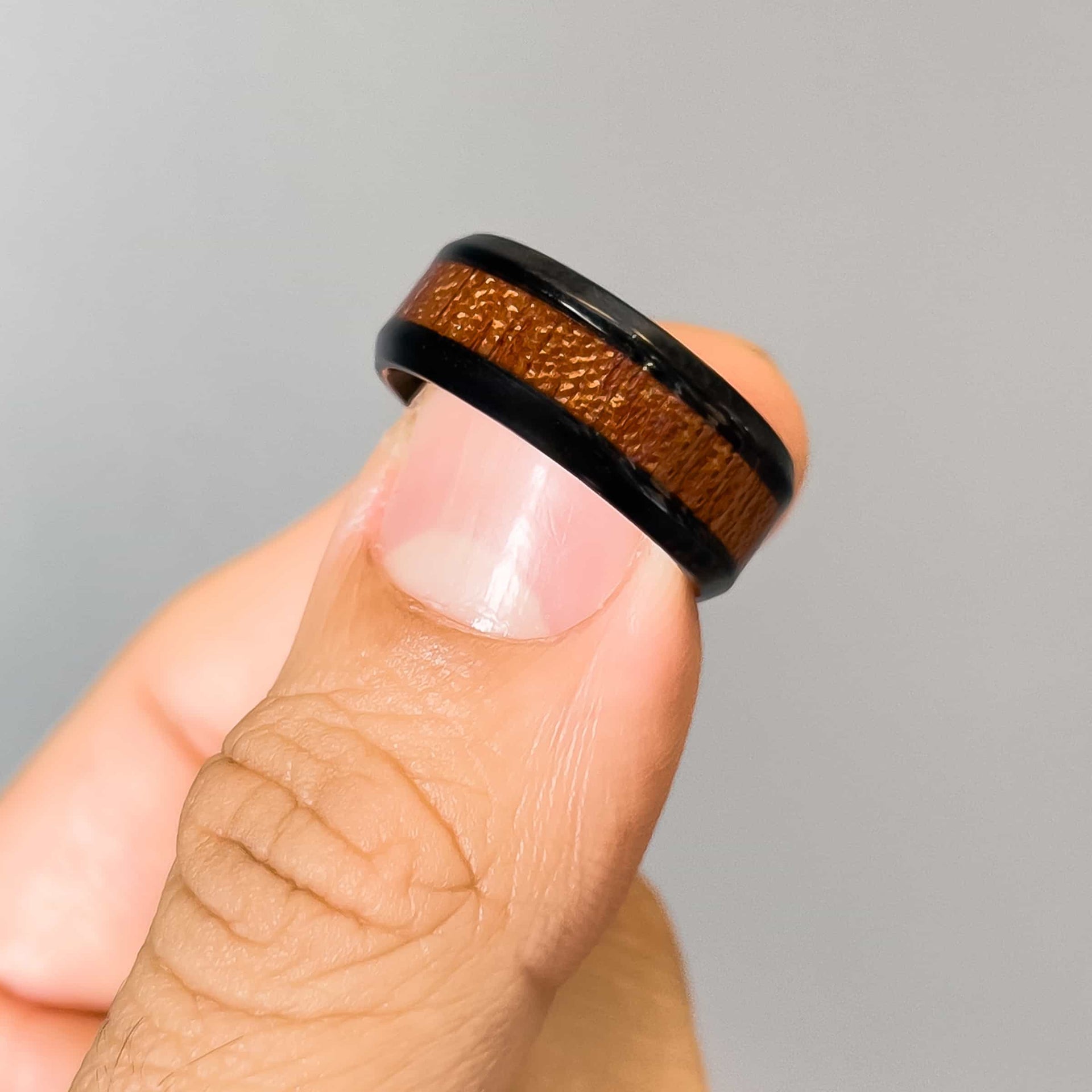 man holding affordable mens wedding band with wood detailing in middle