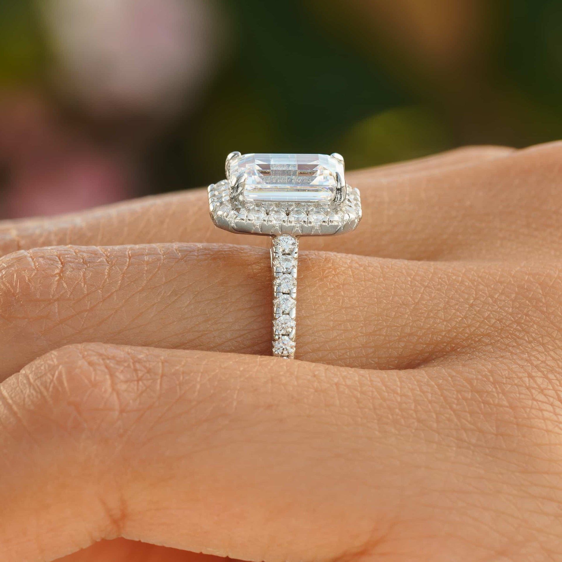 Side profile of silver emerald cut engagement ring with half eternity band detailing