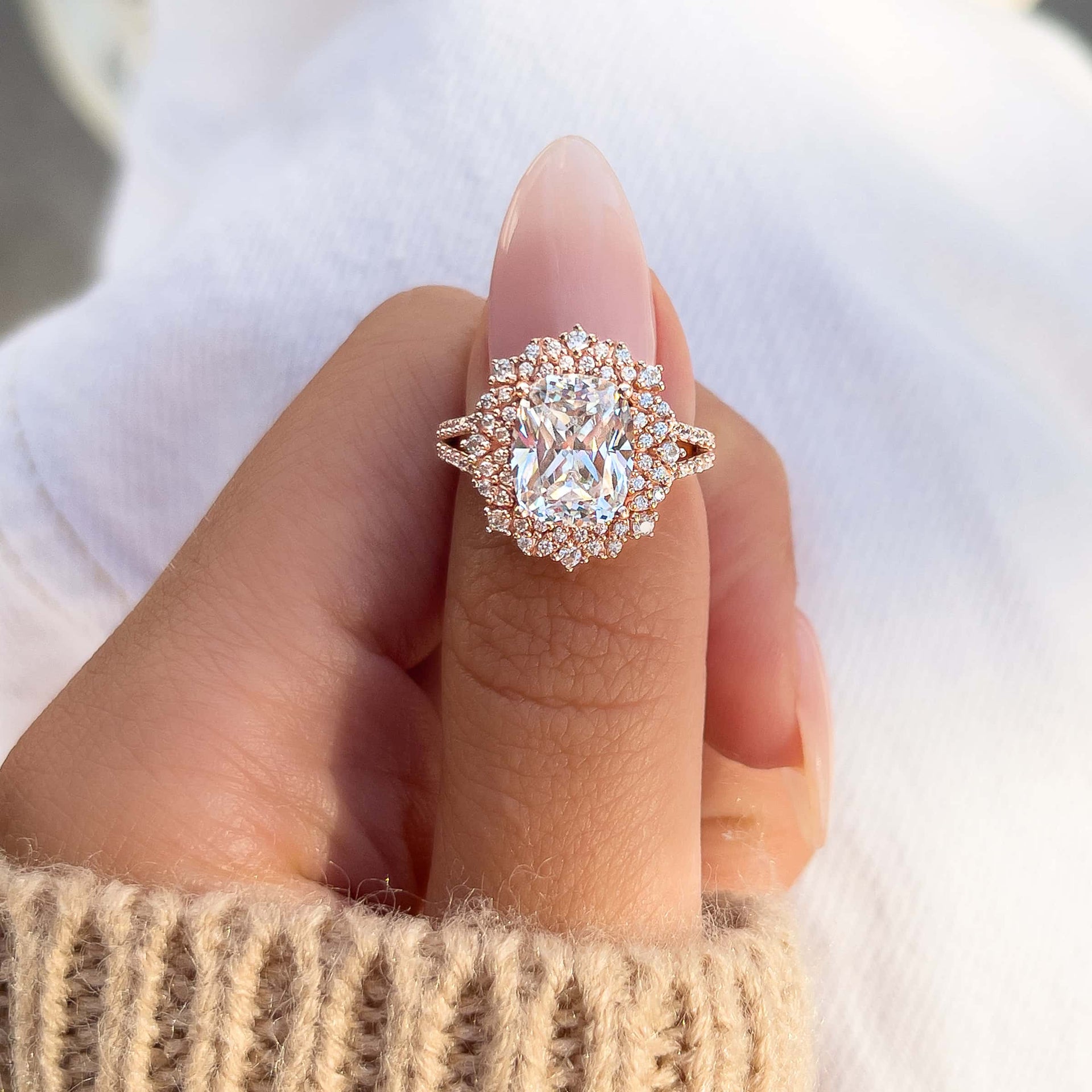 pinching shot of engagement ring on thumb shown in rose gold